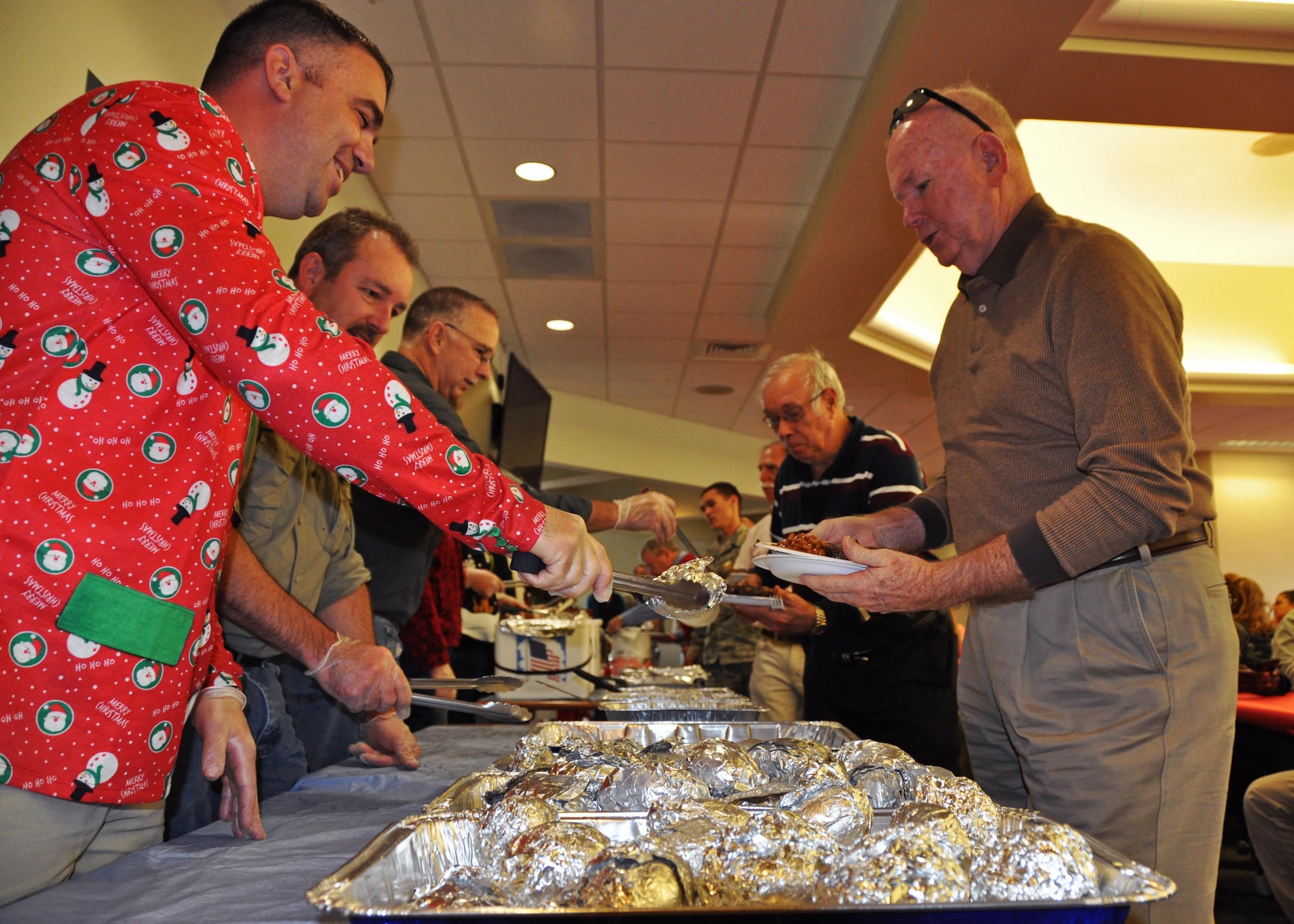 Retired Lt. Gen. James Sherrard, a former 919th Tactical Airlift Group member, moves along a holiday steak luncheon serving line staffed by volunteers from the 919th Special Operations Maintenance Group at Duke Field, Fla., Dec. 16.  Sherrard was one of 10 of the 919th Special Operations Wing's retired former leaders and members invited to tour the base and receive updates on the Air Force Reserve unit’s rapidly evolving mission sets.  (U.S. Air Force photo/Dan Neely)