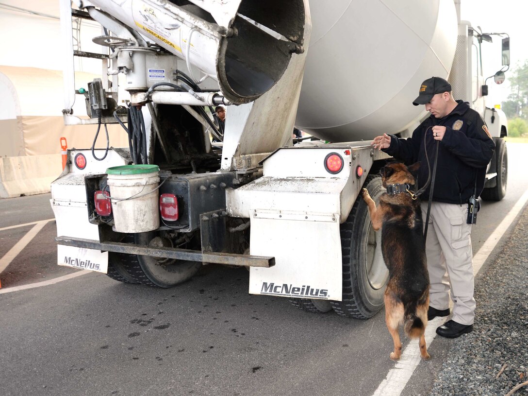 Cpl. Erin Zupko, police officer/K-9 handler, Marine Corps Police Department, Marine Corps Logistics Base Albany, and his military working dog, inspect a commercial vehicle as part of a routine security check at the Mock Road Commercial Truck Gate. All vehicles entering the installation are required to go through rigorous security protocols before access is granted.