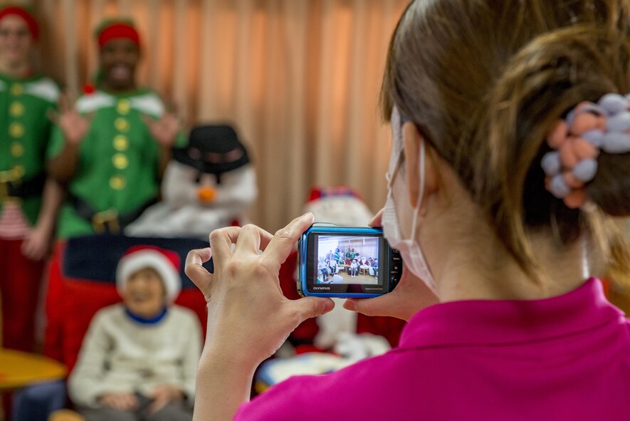 An employee of the Fussa Kotobuki Garden Nursing Home takes a photo of residents with volunteers during a Christmas Eve visit on Dec. 24, 2016, in Fussa, Tokyo, Japan. Volunteers from Yokota Air Base’s Community Center Outreach Program visit the Kotobuki Garden Nursing Home multiple times a year to visit with the residents to provide positive and caring outreach opportunities in the local community. (U.S. Air Force photo by Airman 1st Class Donald Hudson)