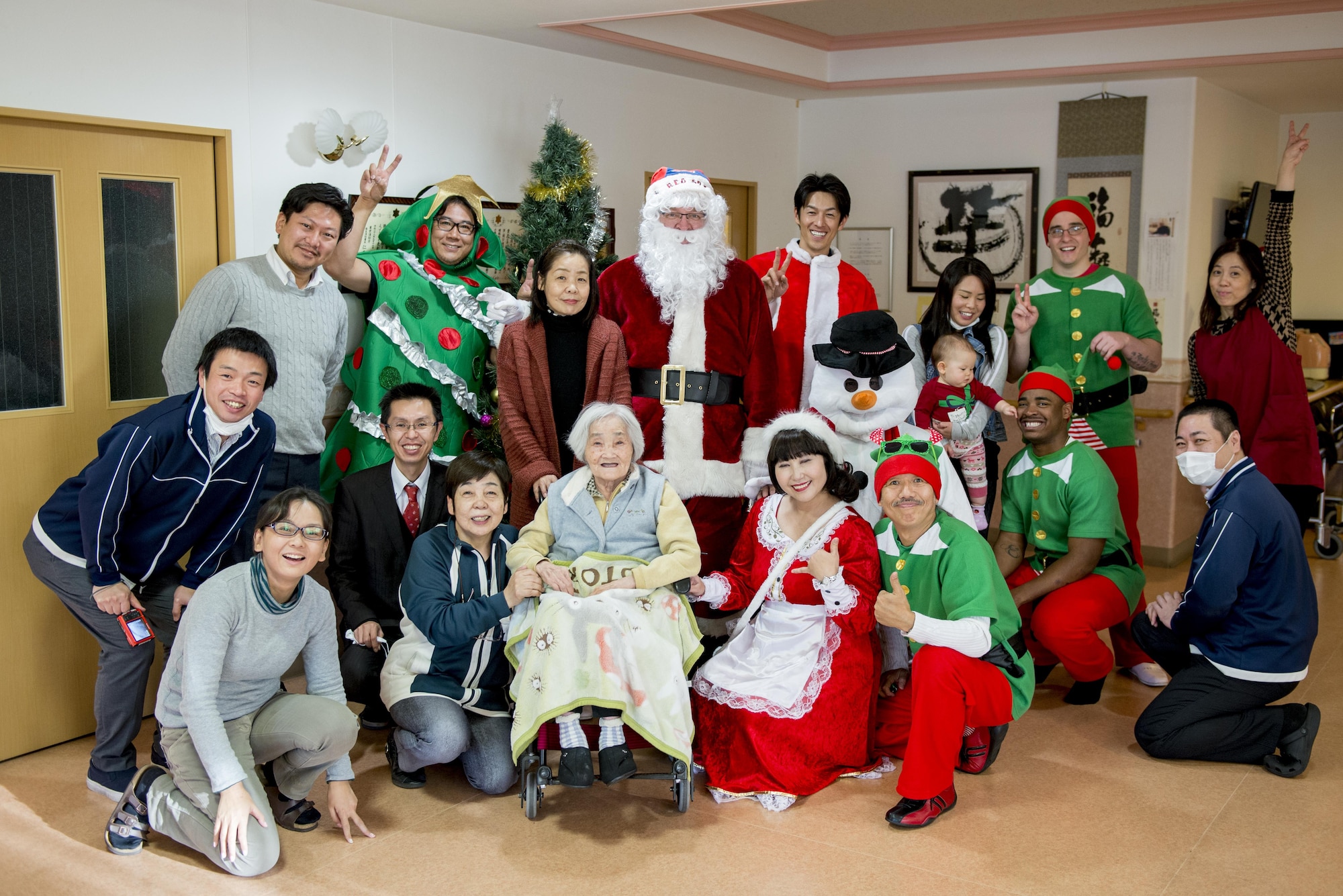 Employees of the Fussa Kotobuki Garden Nursing Home and Yokota Air Base volunteers pose for a photo during a Christmas Eve visit on Dec. 24, 2016, in Fussa, Tokyo, Japan. During visits throughout the years to the Fussa Kotobuki Garden Nursing Home, volunteers have arranged various activities such as the Christmas Eve visits, barbecue lunches, taking residents for walks along the nearby Tama River or going to simply sit and talk with them. (U.S. Air Force photo by Airman 1st Class Donald Hudson)