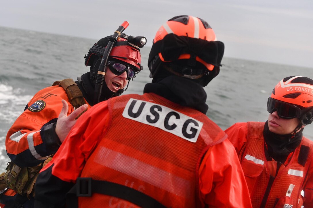 Coast Guardsmen discus a training scenario during hoist training in Hampton Bays, N.Y., Dec. 22, 2016. Air National Guard photo by Staff Sgt. Christopher S. Muncy