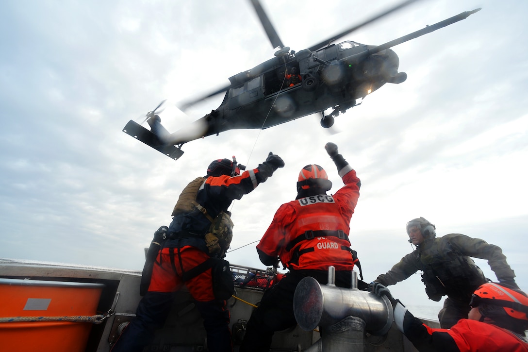 Coast Guardsmen give a thumbs-up to hoist a stretcher with a simulated patient during hoist training in Hampton Bays, N.Y., Dec. 22, 2016. Air National Guard photo by Staff Sgt. Christopher S. Muncy