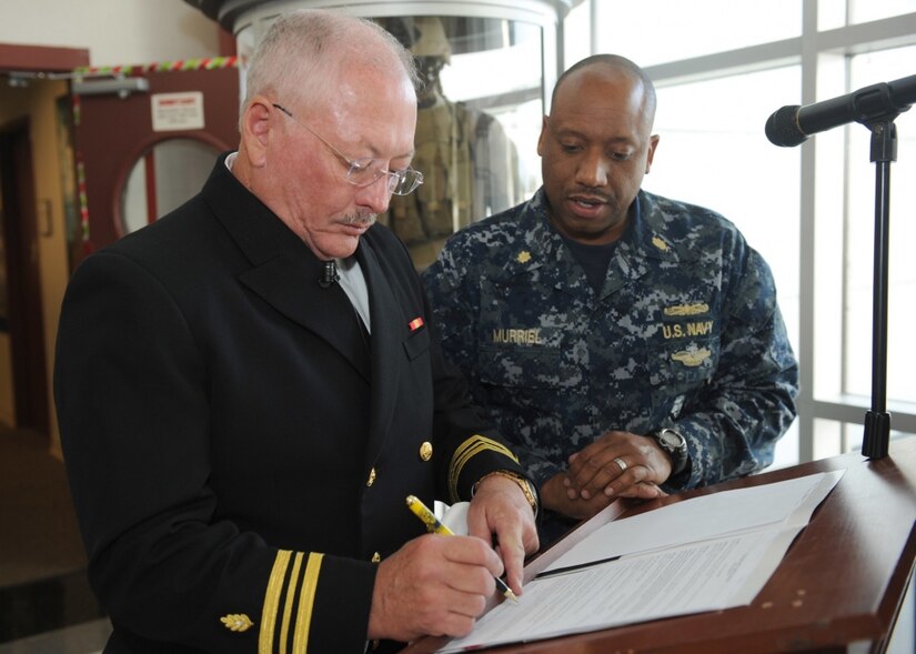 Navy Lt. Cmdr. Charles Wallace, left, signs his commissioning paperwork with Navy Lt. Cmdr. Markeece Murriel, health care administrator at Navy Recruiting Command in Millington, Tenn., Dec. 19, 2016. Following a 27-year career of private practice in plastic surgery, Wallace will now lend his medical expertise as part of the Navy Reserve. Navy photo by Petty Officer 3rd Class Brandon Martin