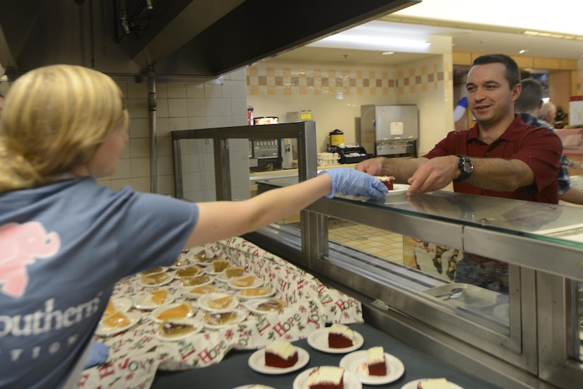 Loren Cole, left, daughter of U.S. Air Force Chief Master Sgt. Todd Cole, 628th Air Base Wing command chief, serves cake to U.S. Air Force 2nd Lt. Brett Betit, right, 628th Civil Engineer Squadron programmer, during Christmas dinner at the Gaylor Dining Facility Dec. 25, 2016. Base leadership and their families helped serve Airmen Christmas dinner.