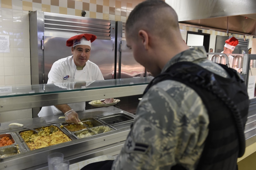 U.S. Air Force Chief Master Sgt. Kristopher Berg, left, 437th AIrlift Wing command chief, serves U.S. Air Force Airman 1st Class Elijah Allen, right, 628th Security Forces Squadron entry controller, Christmas dinner at the Gaylor Dining Facility, Dec. 25, 2016. Members of the dining facility began cooking and prepping the main courses on Dec. 24 and didn’t finish until early Dec. 25.