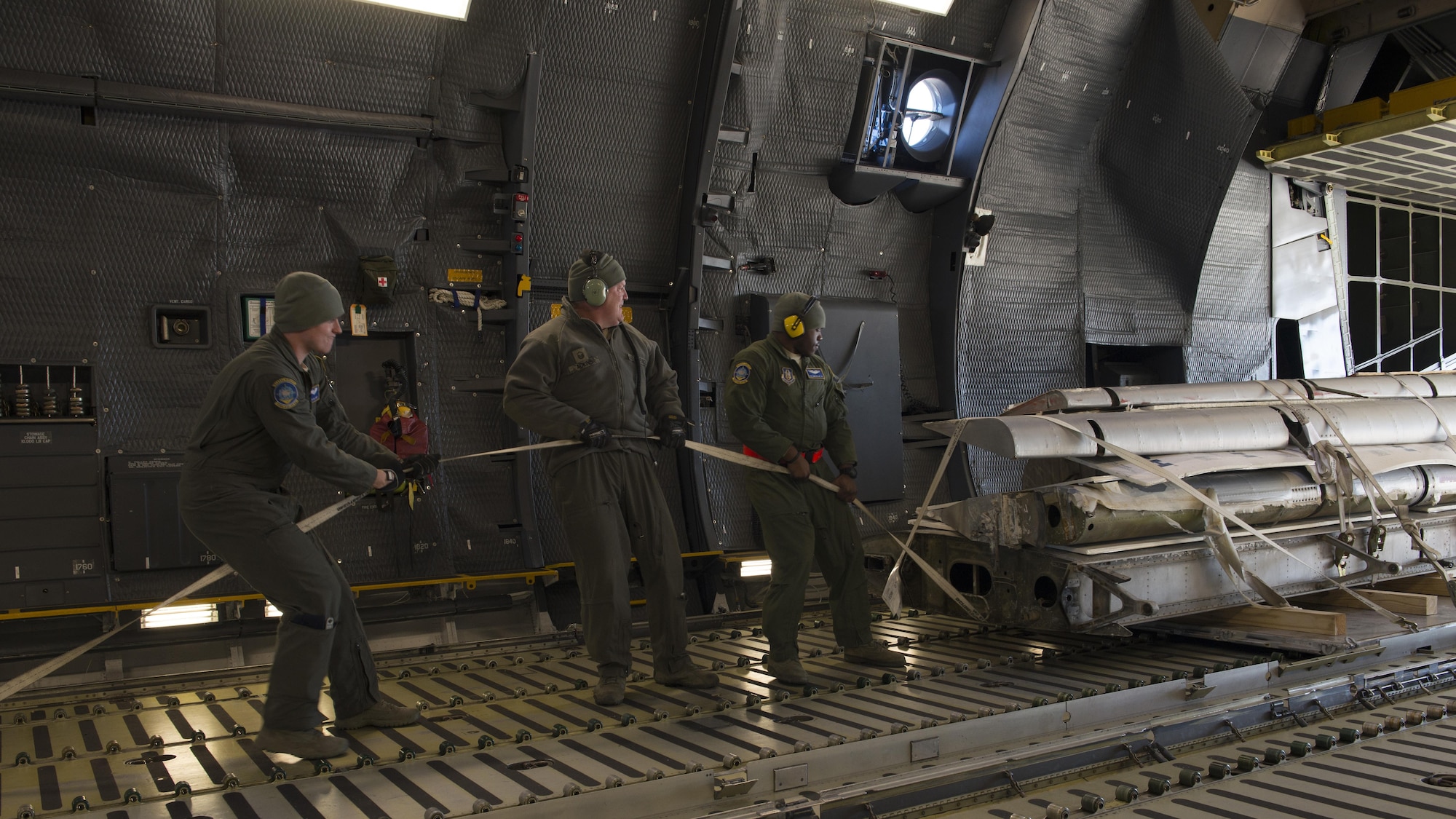 Loadmasters from the 709th Airlift Squadron pull portions of the Fairchild C-119B Flying Boxcar #48-0352 “Am Can Co Special” into the cargo bay of a C-5M Super Galaxy Dec. 19, 2016, at Edwards Air Force Base, Calif. This airlift mission was used as training experience for the new loadmasters. (U.S. Air Force photo by Senior Airman Zachary Cacicia)