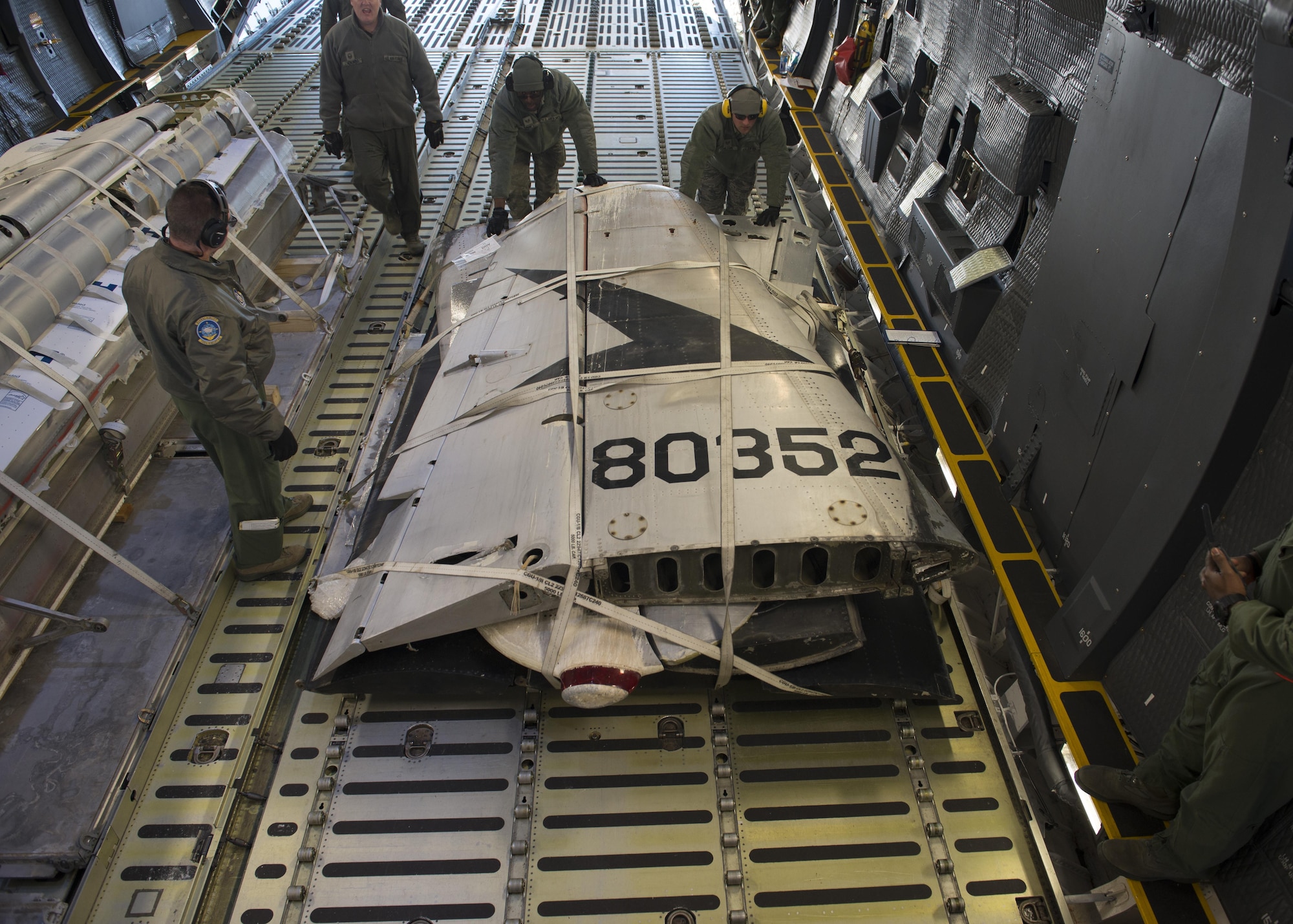 Staff Sgt. Johnathan Barnes, 412th Logistics Readiness Squadron air transportation specialist, and Staff Sgt. Andrew Chilcoat, 412th LRS air transportation specialist, push the palletized tail section of the Fairchild C-119B Flying Boxcar #48-0352 “Am Can Co Special” into a C-5M Super Galaxy’s cargo bay Dec. 19, 2016, at Edwards Air Force Base, Calif. Barnes and Chilcoat, both stationed at Edwards AFB, were vital in logistic support of this mission. (U.S. Air Force photo by Senior Airman Zachary Cacicia)