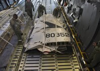 Staff Sgt. Johnathan Barnes, 412th Logistics Readiness Squadron air transportation specialist, and Staff Sgt. Andrew Chilcoat, 412th LRS air transportation specialist, push the palletized tail section of the Fairchild C-119B Flying Boxcar #48-0352 “Am Can Co Special” into a C-5M Super Galaxy’s cargo bay Dec. 19, 2016, at Edwards Air Force Base, Calif. Barnes and Chilcoat, both stationed at Edwards AFB, were vital in logistic support of this mission. (U.S. Air Force photo by Senior Airman Zachary Cacicia)