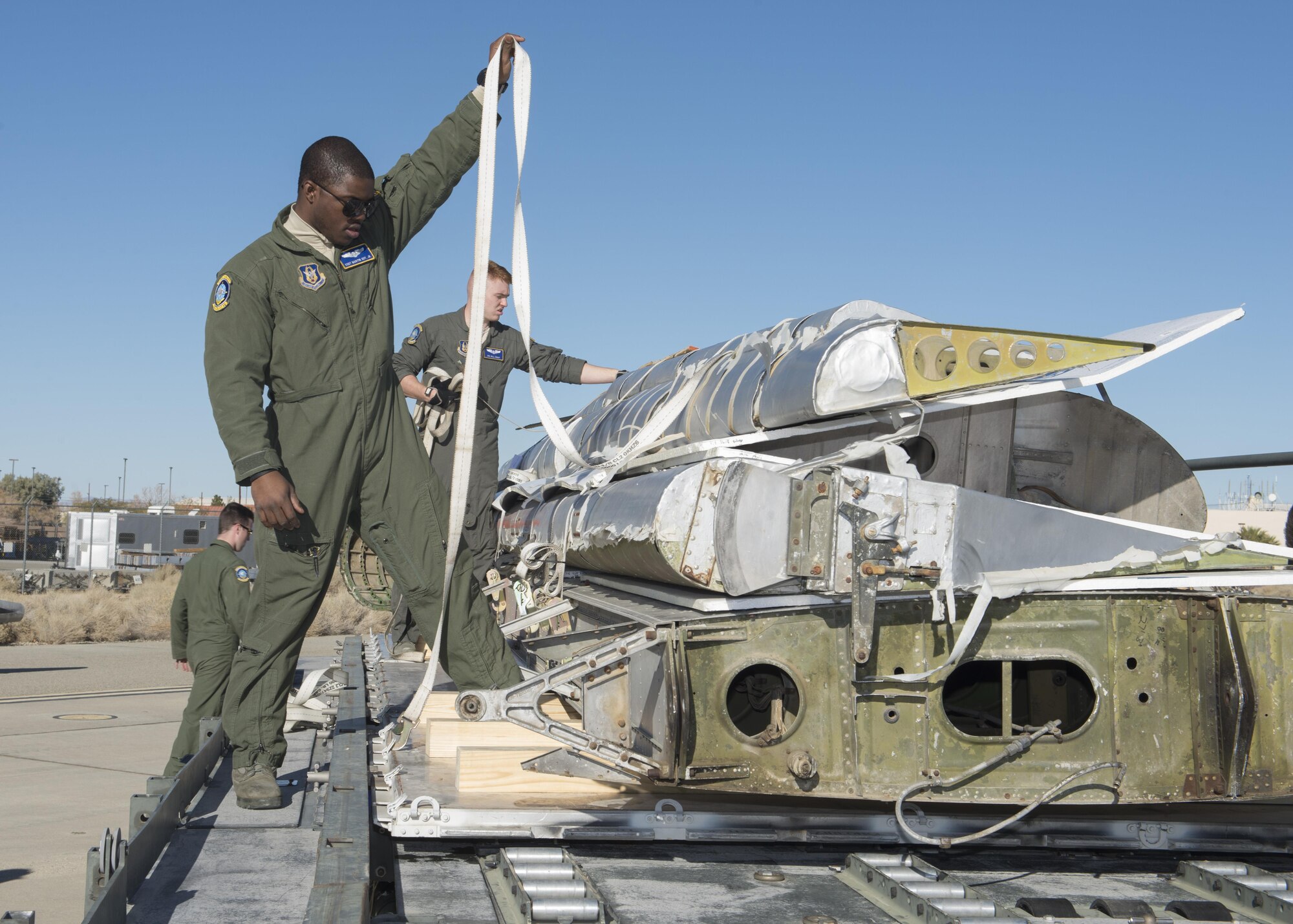 Staff Sgt. Martin Guy, 709th Airlift Squadron loadmaster, straps down portions of the Fairchild C-119B Flying Boxcar #48-0352 “Am Can Co Special” to a pallet during a mission to bring it to the AMC Museum via a C-5M Super Galaxy airlifter Dec. 17, 2016, at Edwards Air Force Base, Calif. Restoration work on the C-119 will take a minimum of two years. (U.S. Air Force photo by Senior Airman Zachary Cacicia)