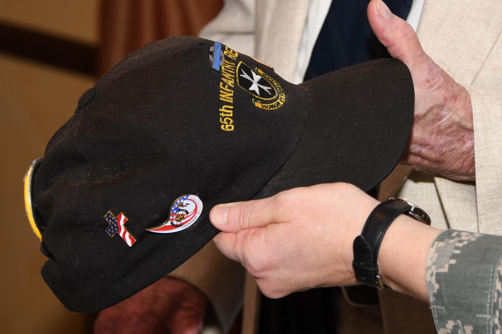 U.S. Air Force Chief Master Sgt. Shelley Cohen, 307th Bomb Wing command chief, gets an up close look at a U.S. Army 65th Infantry Regiment cap during a luncheon honoring veterans of The Battle of Chosin Reservoir Dec. 22, 2016 at Barksdale Air Force Base, La.  The battle was part of the Korean conflict in which American troops found themselves surrounded by enemy forces.   The regiment served as the rear guard that helped U.S. soldiers and Marines break out to safety despite being vastly outnumbered and fighting in sub-zero temperatures. The luncheon was part of a week-long slate of events sponsored by the Independence Bowl Foundation to honor the veterans. (U.S Air Force photo by Tech. Sgt. Ted Daigle/Released)