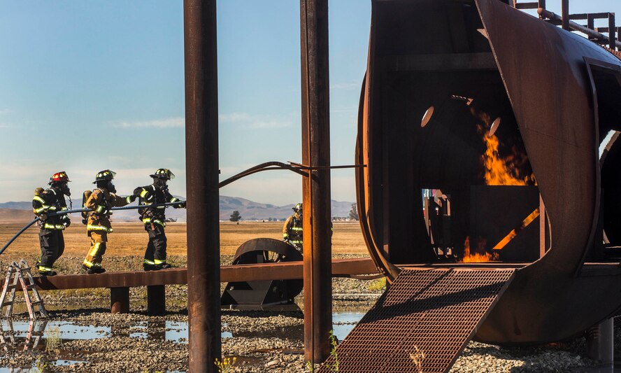 Fire Protection specialist from the 60th Civil Engineering Squadron Travis Air Force Base, Calif., hone their skills using the live aircraft trainer Oct. 21, 2016. The trainer simulates fires in different parts of an aircraft’s body allowing the fire fighters to practice on engine, cockpit, passenger and cargo areas. (US Air Force Photo by T.C. Perkins Jr.)