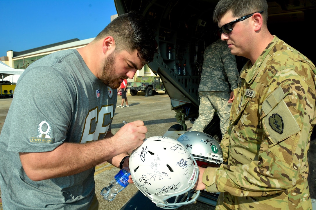 Pittsburgh Steelers guard David DeCastro signs a football helmet for Army Chief Warrant Officer 4 Justin Watts during the 2016 Pro Bowl Draft on Wheeler Army Airfield, Jan. 27, 2016. Watts is assigned to the 25th Combat Aviation Brigade, 25th Infantry Division. U.S. Army photo by Sgt. 1st Class John Brown