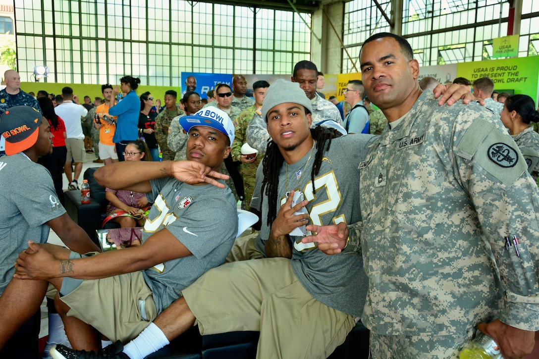 Kansas City Chiefs corner back Marcus Peters and San Diego Chargers corner back Jason Verrett stop for a photo opportunity with Army Sgt. 1st Class Kevin Edmondson while watching the 2016 Pro Bowl Draft show on Wheeler Army Airfield, Hawaii, Jan. 27, 2016. Verrett is assigned to the Regional Health Command-Pacific. U.S. Army photo by Sgt. 1st Class John Brown