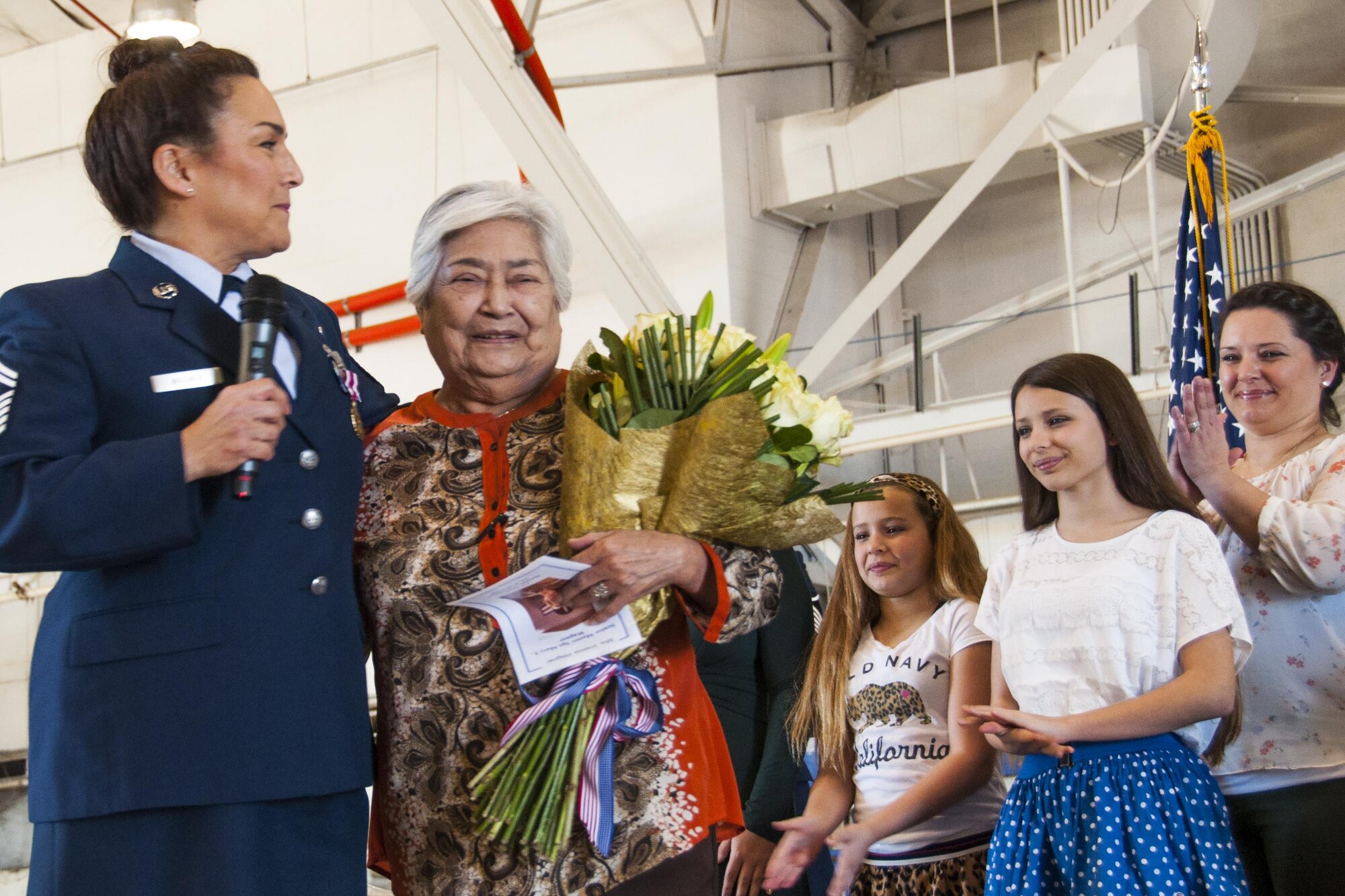 U.S. Air Force Senior Master Sgt. Mary Wagner presents her mother, Imelda Wagner, with a bouquet of roses at Barksdale Air Force Base, La., Jan. 30, 2016, as her granddaughters and daughter look on.  The presentation was given during Wagner's retirement ceremony in appreciation of her mother's support.  Wagner told the assembly how her mother always stood ready to take care of her children during deployments and unit training assemblies. Wagner retired after 38 years of service. (U.S. Air Force photo by Tech. Sgt. Ted Daigle/released)