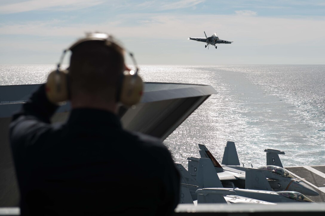 Navy Lt. Joseph Garrett observes an F/A-18F Super Hornet as it prepares to land on the flight deck of the USS John C. Stennis in the Pacific Ocean, Jan. 22, 2016. Navy photo by Seaman Dakota Rayburn
