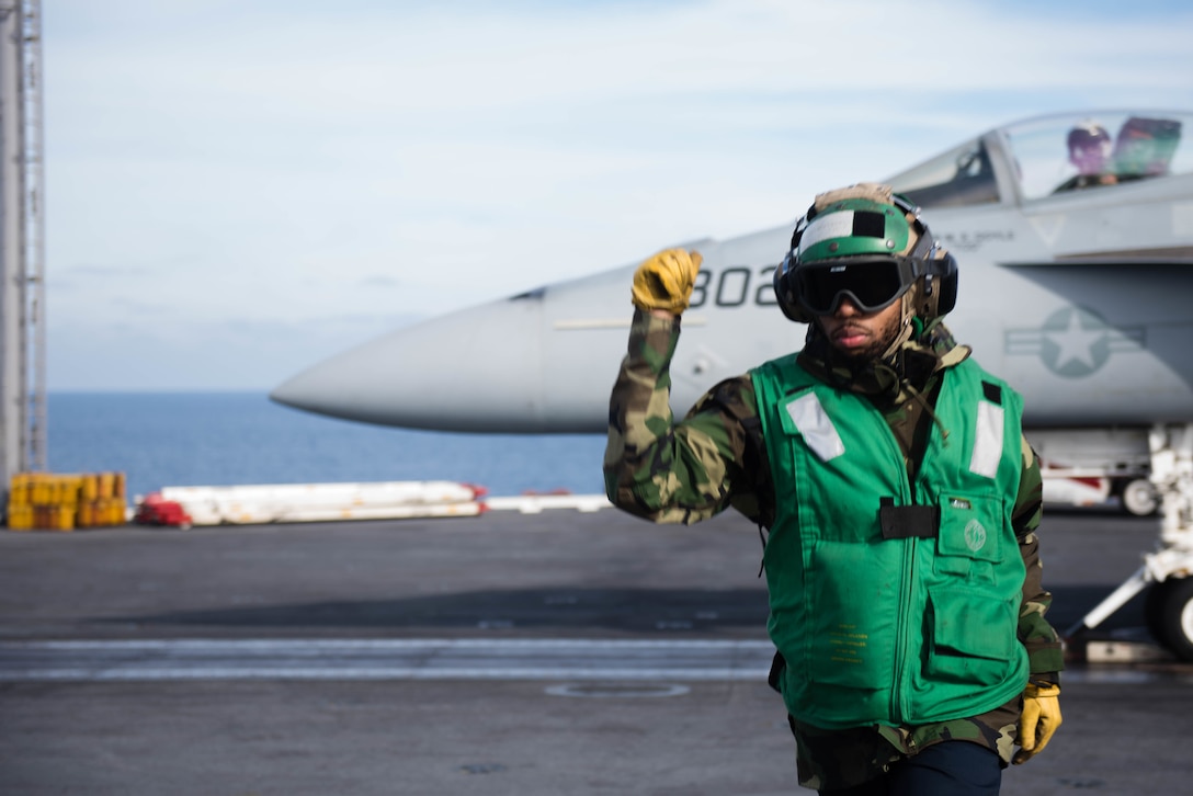 Navy Petty Officer 2nd Class Antwan Greene gives the signal to clear the catapult after conducting a final check on an F/A-18E Super Hornet before takeoff on the flight deck of the USS John C. Stennis in the Pacific Ocean, Jan. 22, 2016. Greene is an aviation boatswain's mate. Navy photo by Petty Officer 3rd Class Kenneth Rodriguez Santiago