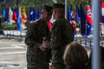 U.S. Marine Corps Col. Paul J. Nugent hands off the microphone to Lt. Col. Michael Nakonieczny, commanding officer, Headquarters Battalion, 1st Marine Division, to address the crowd during a change of command ceremony at Marine Corps Base Camp Pendleton, Calif., Jan. 7, 2016. A change of command is a military tradition that represents a formal transfer of authority and responsibility for a unit from one commanding officer to another. (U.S. Marine Corps photo by Lance Cpl. Nathaniel Castillo, 1st Marine Division Combat Camera/Released)