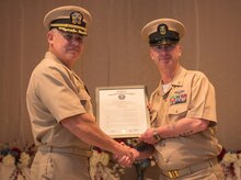 (From left to right) Navy Captain Charles Phillip, Naval Munitions Command Atlantic Unit Charleston commander, presents the document promoting former Master Chief Petty Officer Jason Roach to CWO3 at the Red Bank Club on Joint Base Charleston – Naval Weapons Station, S.C., on Jan. 29, 2016. Roach’s next duty station is aboard the USS Eisenhower, a nuclear-powered aircraft carrier. (U.S. Air Force photo/Airman 1st Class Thomas T. Charlton)