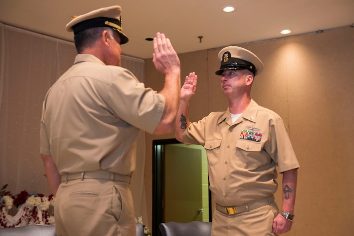 (From left to right) Navy Captain Charles Phillip, Navy Munitions Command Atlanta Unit Charleston commander, swears former MCPO Jason Roach in as a CWO3 during Roach’s commissioning ceremony at the Red Bank Club on Joint Base Charleston – Naval Weapons Station, S.C., on Jan. 29, 2016. (U.S. Air Force photo/Airman 1st Class Thomas T. Charlton)
