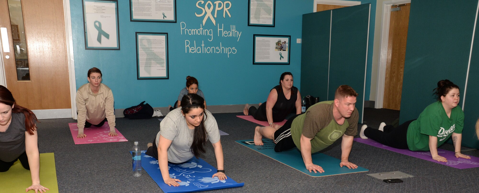 Team Mildenhall members and their families take part in a yoga class hosted by the 100th Air Refueling Wing Sexual Assault Prevention and Response office Jan. 21, 2016, on RAF Mildenhall, England. The new classes are held at various days, times and locations on base and are open to all abilities. (U.S. Air Force photo by Gina Randall/Released)