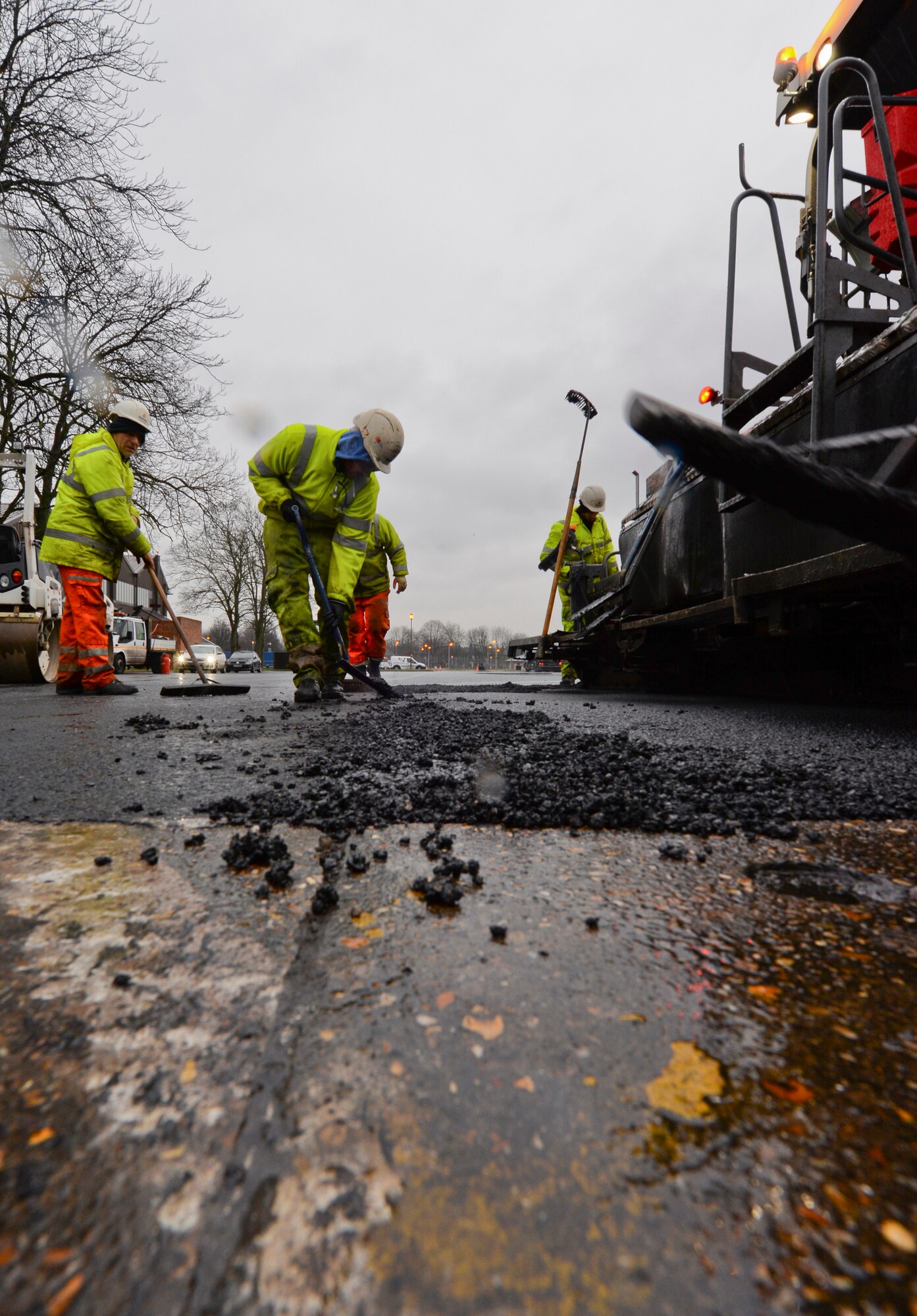 Contracted construction workers spread hot tarmac over the 100th Logistics Readiness Squadron Vehicle Operations yard Jan. 22, 2016, on RAF Mildenhall, England. The temperature of the asphalt starts out at 392 degrees Fahrenheit when leaving the manufacturing plant and has to be at a high temperature so it is malleable and can be easily moved around and smoothed out. (U.S. Air Force photo by Staff Sgt. Micaiah Anthony/Released)