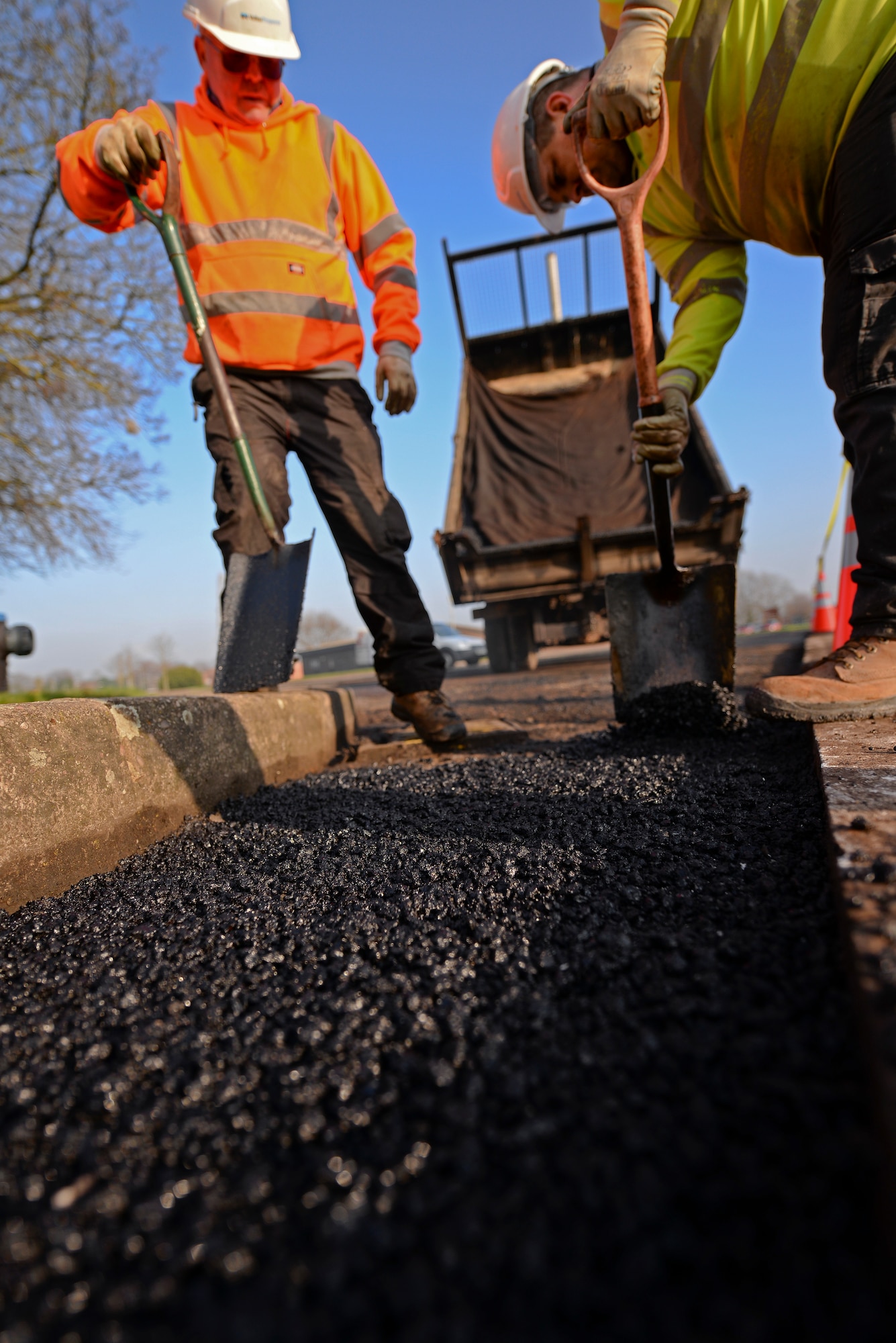 Contracted construction workers fill a hole with asphalt in the 100th Logistics Readiness Squadron Vehicle Operations yard Jan. 20, 2016, on RAF Mildenhall, England. To resurface the yard, construction workers must break up and remove the old tarmac and fill in any uneven surfaces before applying the final layer of asphalt. (U.S. Air Force photo by Staff Sgt. Micaiah Anthony/Released)
