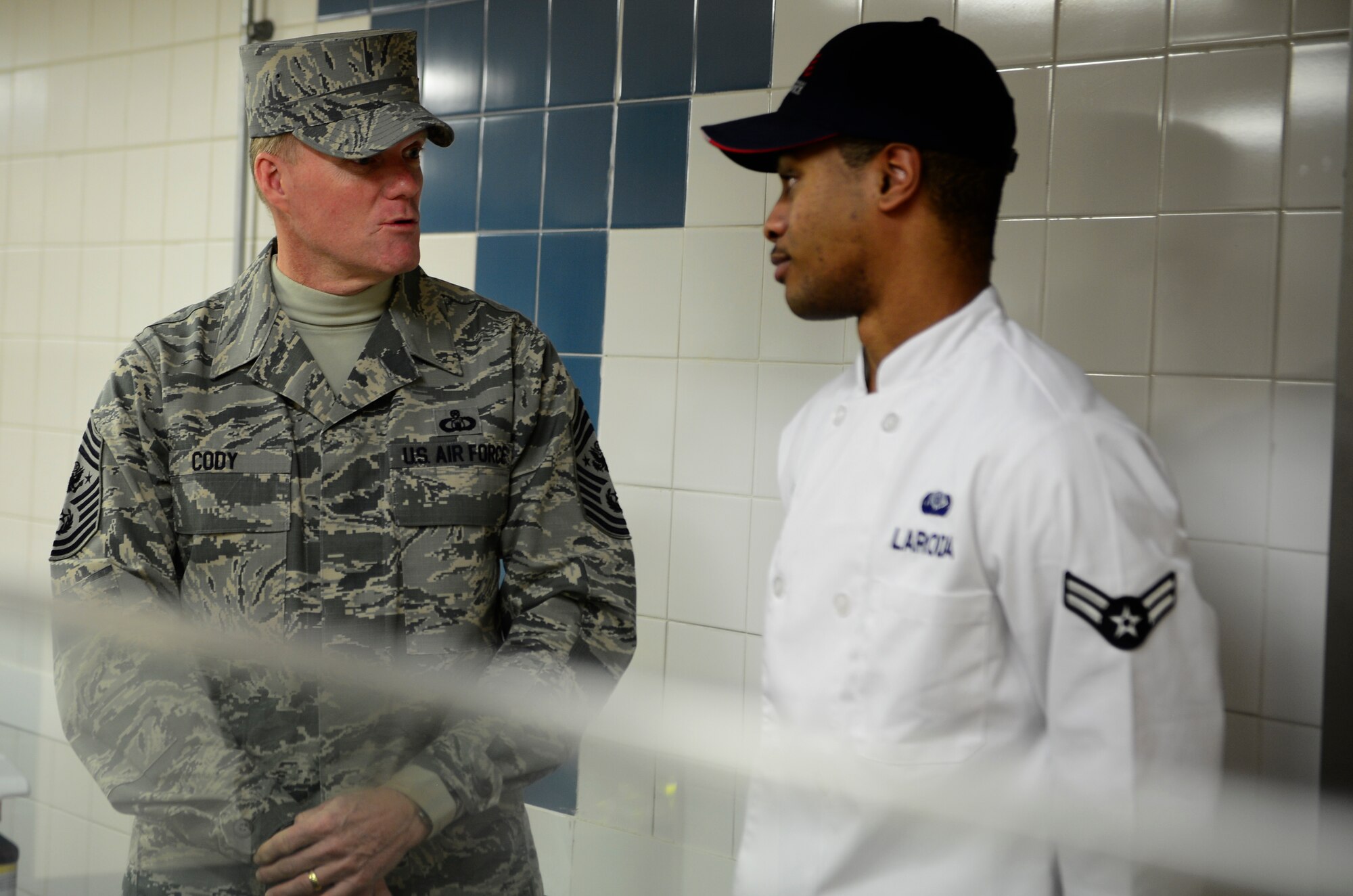 Chief Master Sgt. of the Air Force James Cody, speaks with Airman 1st Class Justin Loroda, 48th Force Support Squadron food service specialist, during his visit to Royal Air Force Lakenheath, England, January 28, 2016. Cody’s visit to the base was part of his trip to Europe to tour bases throughout U.S. Air Forces in Europe. (U.S. Air Force photo by Senior Airman Dawn M. Weber/Released)