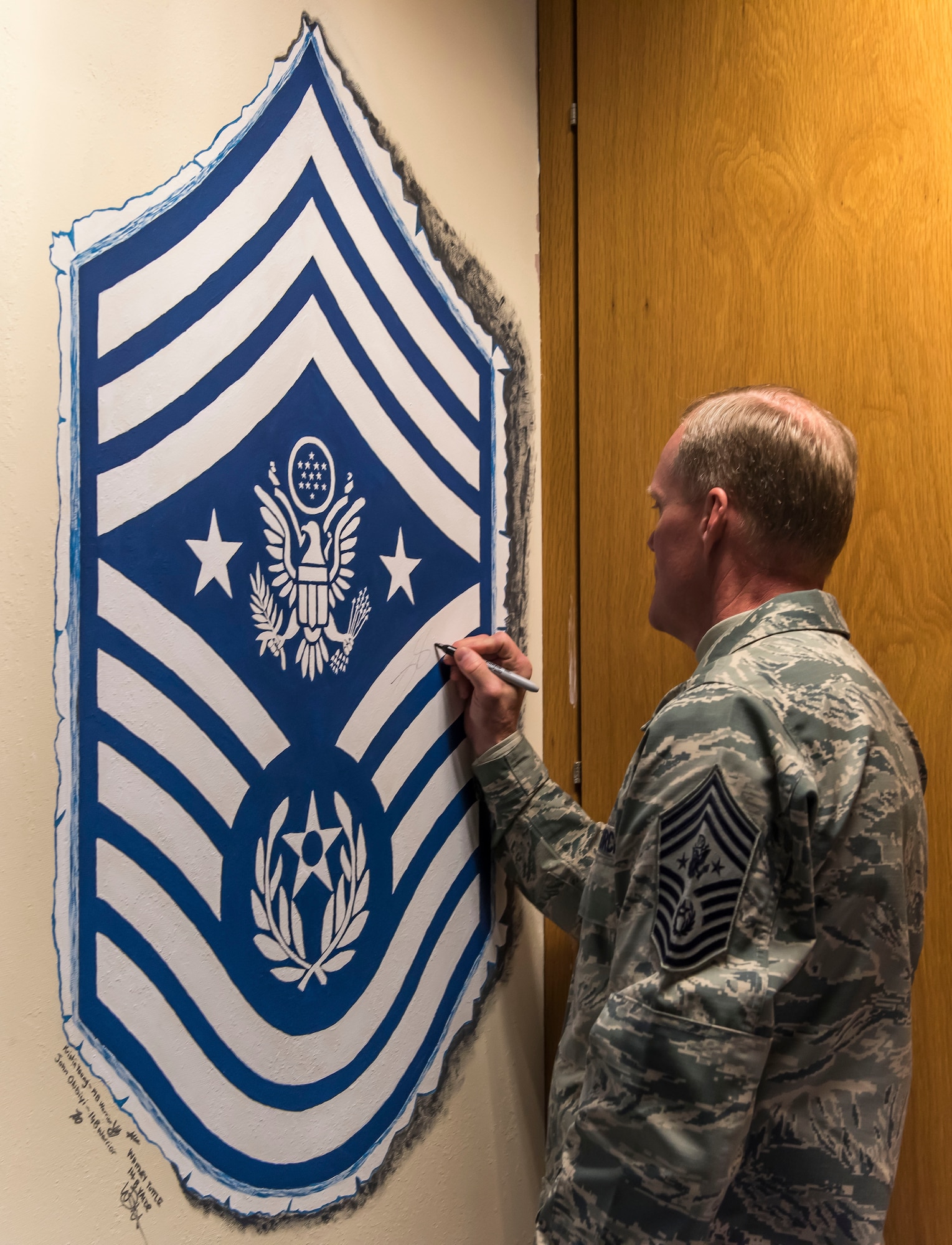 Chief Master Sgt. of the Air Force James Cody signs the CMSAF mural on the wall at Mathies Airman Leadership School on Royal Air Force Feltwell, England, Jan. 29, 2016. Cody visited the Liberty Wing to discuss a variety of topics and to express his appreciation for the way Liberty Airmen execute the mission and strive for excellence. (U.S. Air Force photo/Senior Airman Trevor T. McBride/Released)