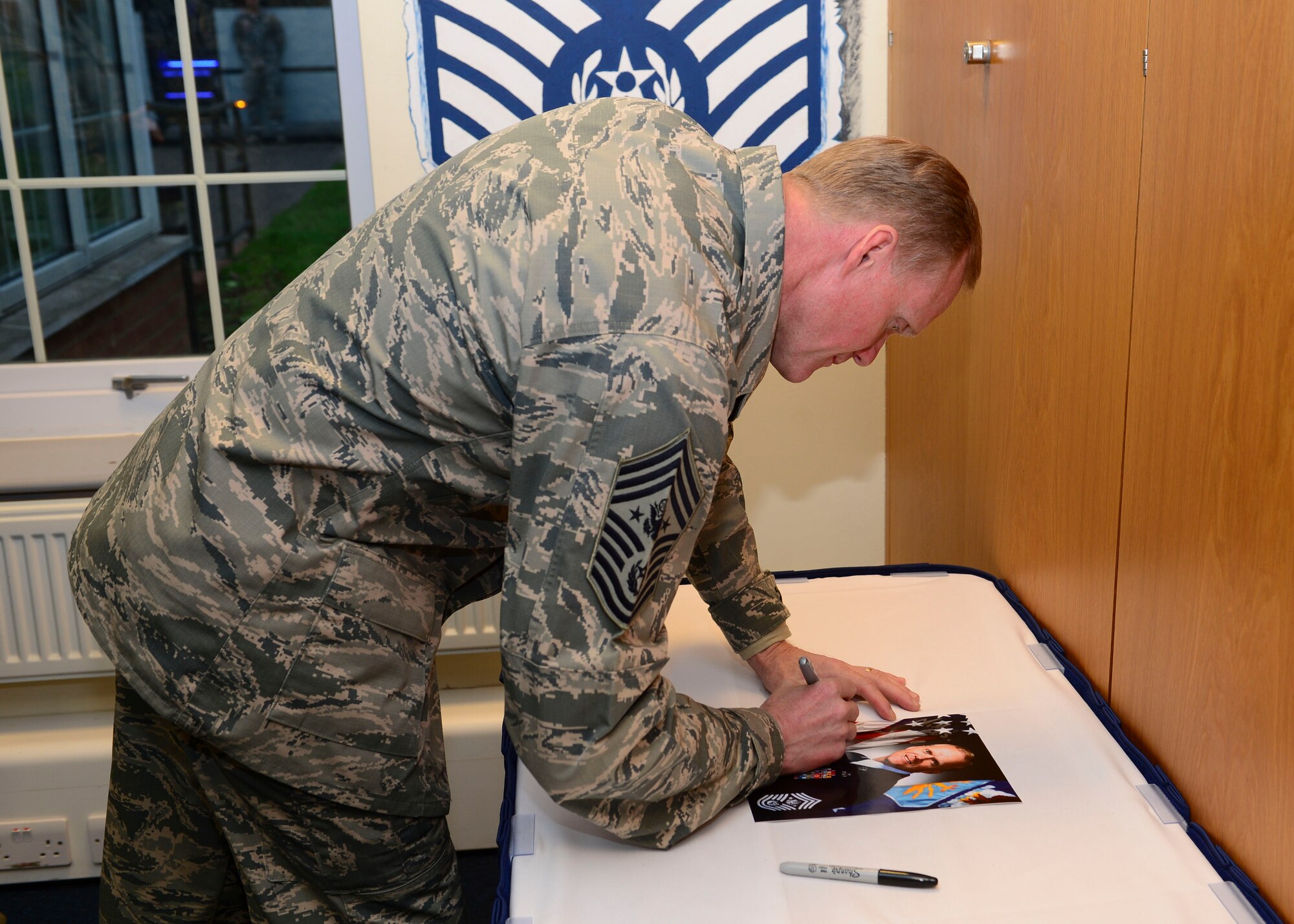 Chief Master Sgt. of the Air Force James Cody autographed a photo of himself at the Mathies Airman Leadership School at Royal Air Force Feltwell, England, Jan. 29, 2016. Cody discussed a variety of topics and expressed his appreciation for the class of future leaders. (U.S. Air Force photo by Senior Airman Nigel Sandridge/Released)