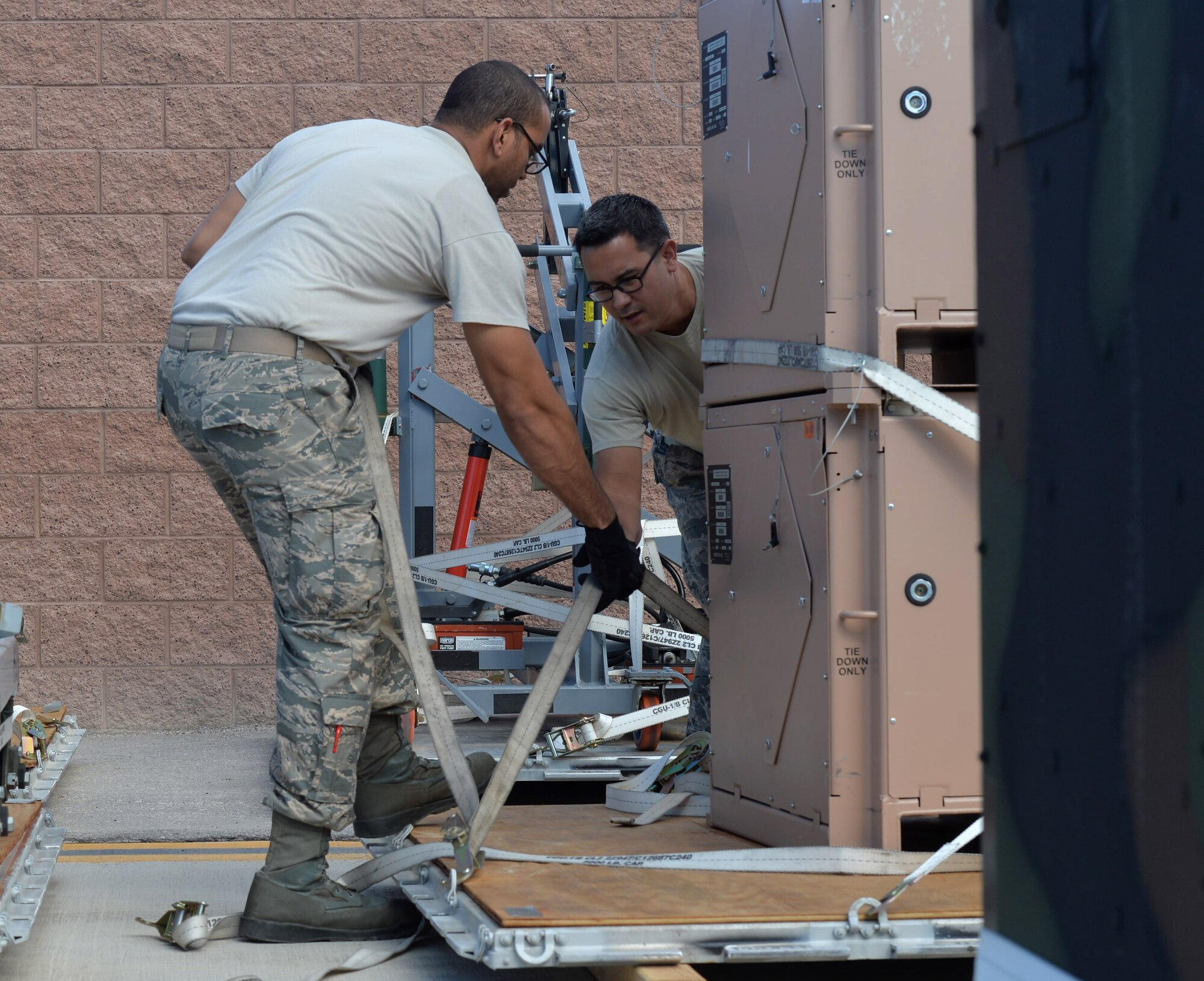 Staff Sgt. Israel, 432nd Maintenance Squadron Aerospace Ground Equipment craftsman, left, and Tech. Sgt. Nicholas, 432nd MXS AGE craftsman, right, secure safety restraints on equipment Oct. 6, 2015, at Creech Air Force Base, Nevada. The 432nd AGE shop sends packages of ground support equipment to deployed locations to support remotely piloted aircraft missions abroad. (U.S. Air Force photo by Senior Airman Christian Clausen/Released)