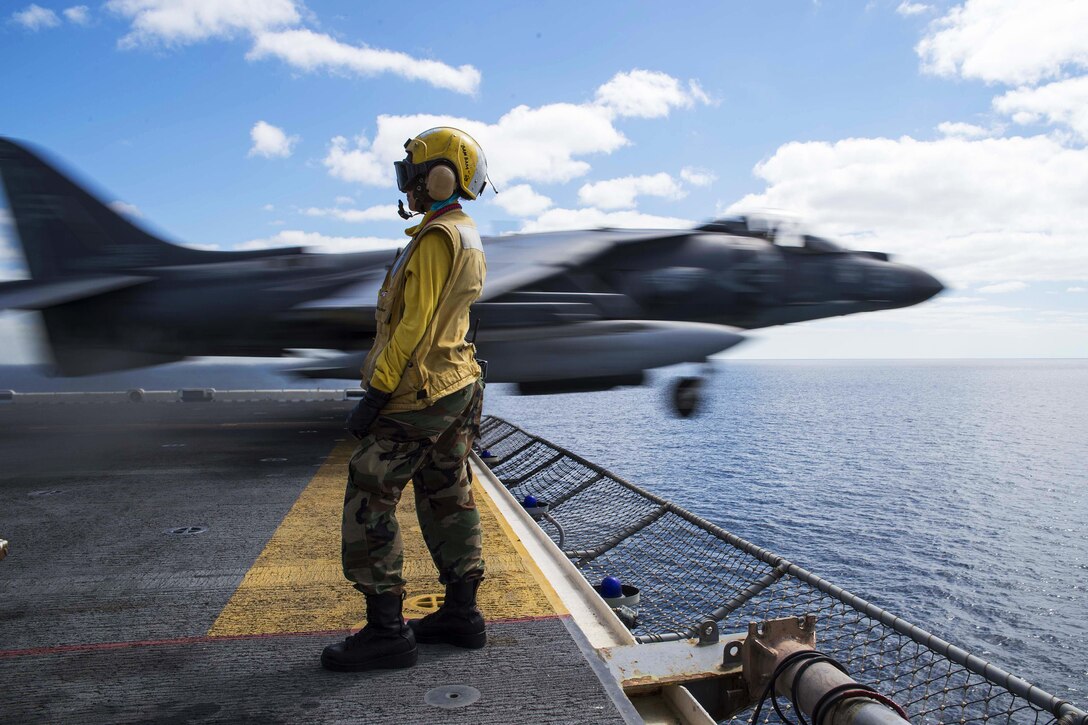 Navy Petty Officer 3rd Class Sarahkate Barambangan looks on as an AV-8B Harrier takes off from the flight deck of the USS Kearsarge in the Gulf of Oman, Jan. 26, 2016. The Kearsarge is deployed to support security efforts in the U.S. 5th Fleet area of responsibility. Navy photo by Petty Officer 3rd Class Tyler Preston