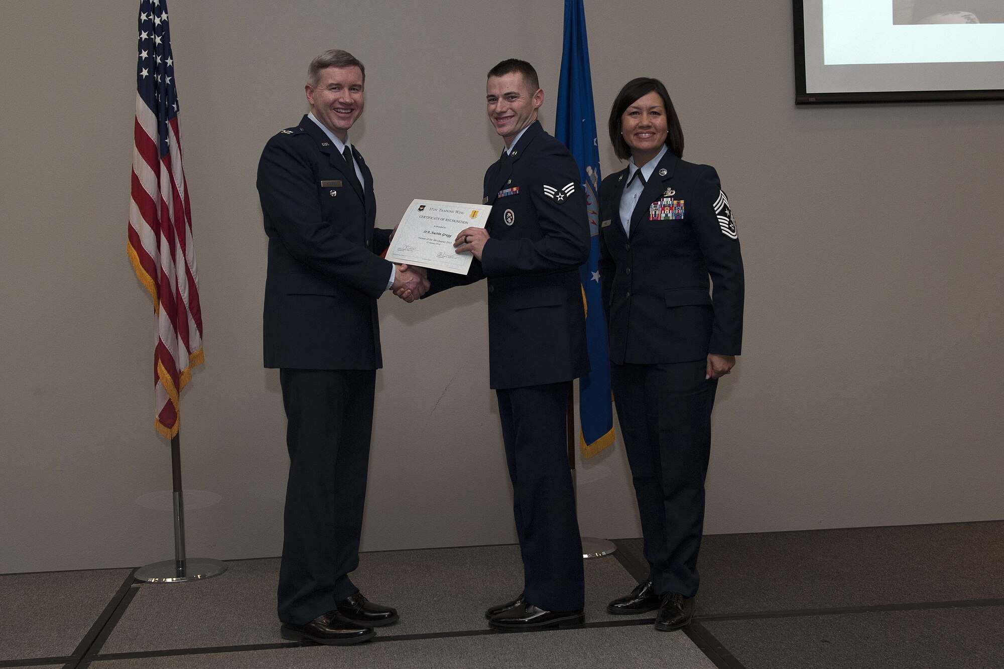 U.S. Air Force Col. Terry J. Hamrick, 17th Training Wing Vice Commander, and Chief Master Sgt. JoAnne S. Bass, 17th TRW Command Chief, present the Dorm Room of the Quarter award to Senior Airman Austin Gregg, 17th Medical Support Squadron, during the wing quarterly awards ceremony at the Event Center on Goodfellow Air Force Base, Texas, Jan. 29, 2016. (U.S. Air Force photo by Airman 1st Class Caelynn Ferguson/Released)