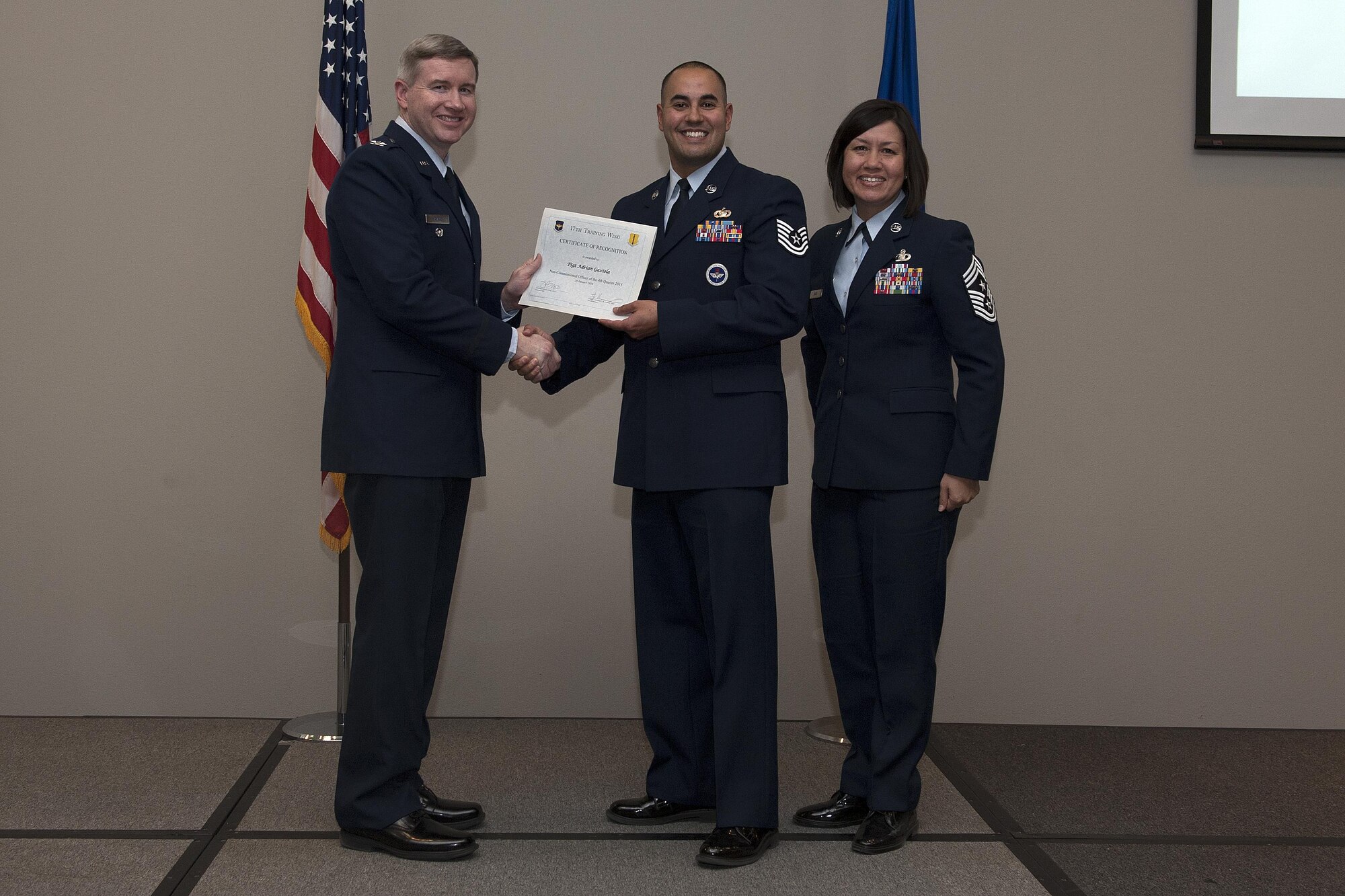 U.S. Air Force Col. Terry J. Hamrick, 17th Training Wing Vice Commander, and Chief Master Sgt. JoAnne S. Bass, 17th TRW Command Chief, present the Non-Commissioned Officer of the Quarter award to Tech. Sgt. Adrian Gaxiola, 315th Training Squadron, during the wing quarterly awards ceremony at the Event Center on Goodfellow Air Force Base, Texas, Jan. 29, 2016. (U.S. Air Force photo by Airman 1st Class Caelynn Ferguson/Released)