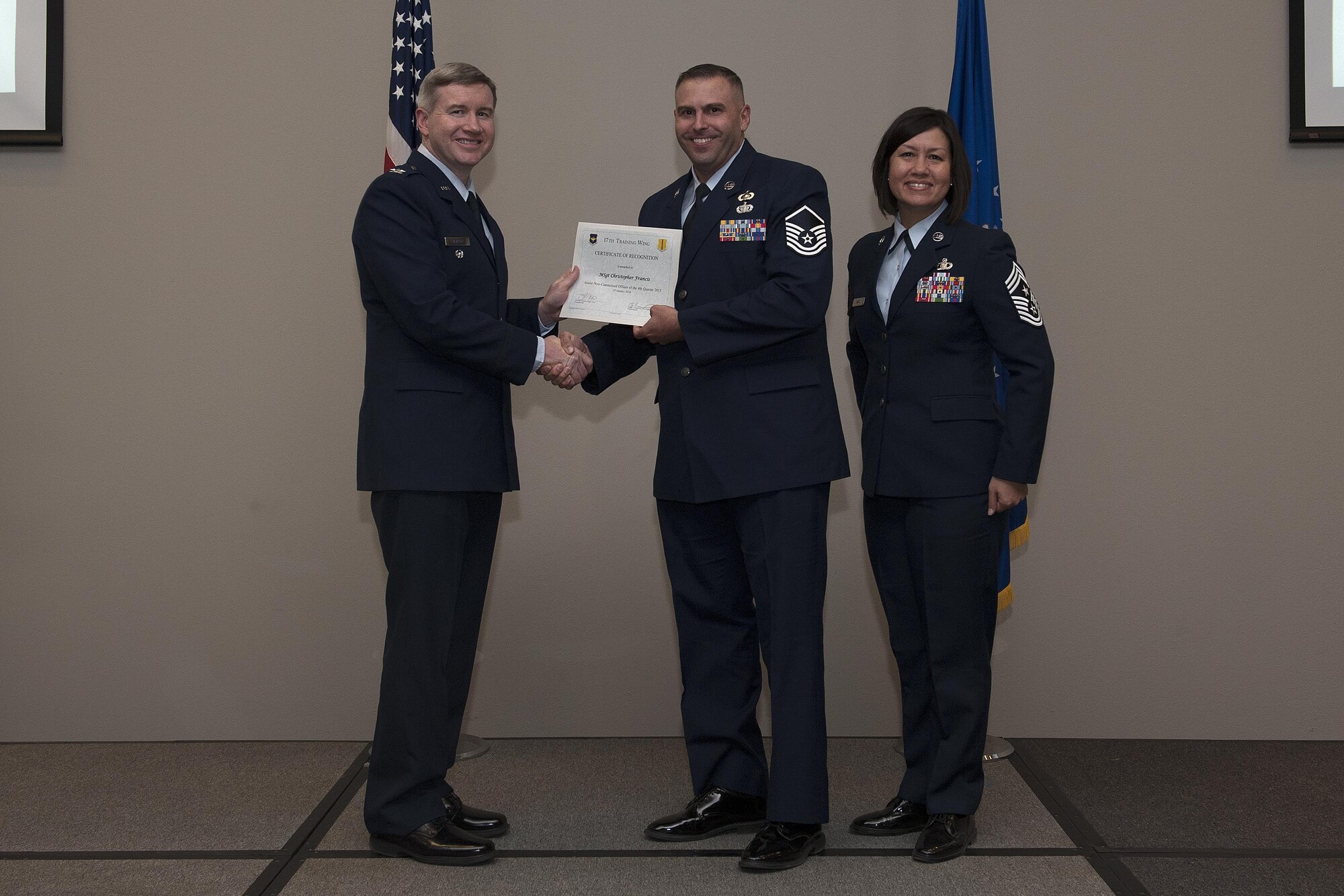 U.S. Air Force Col. Terry J. Hamrick, 17th Training Wing Vice Commander, and Chief Master Sgt. JoAnne S. Bass, 17th TRW Command Chief, present the Senior Non-Commissioned Officer of the Quarter award to Master Sgt. Christopher Francis, 17th Contracting Squadron, during the wing quarterly awards ceremony at the Event Center on Goodfellow Air Force Base, Texas, Jan. 29, 2016. (U.S. Air Force photo by Airman 1st Class Caelynn Ferguson/Released)