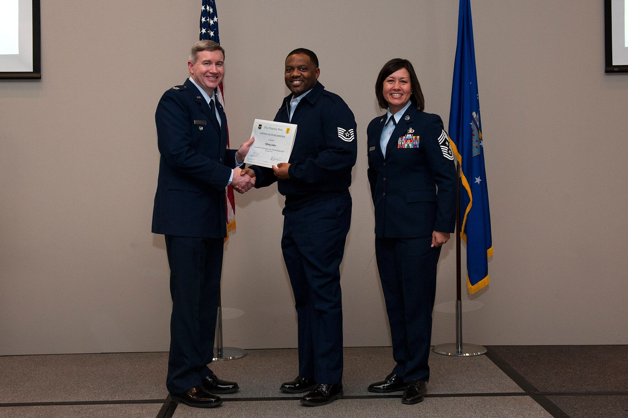 U.S. Air Force Col. Terry J. Hamrick, 17th Training Wing Vice Commander, and Chief Master Sgt. JoAnne S. Bass, 17th TRW Command Chief, present the Civilian Category I Non-Supervisory of the Quarter award to Tech. Sgt. Lewis Sellers, 17th Medical Operations Squadron, on behalf of Tiffany Sellers, 17th MDOS, during the wing quarterly awards ceremony at the Event Center on Goodfellow Air Force Base, Texas, Jan. 29, 2016. (U.S. Air Force photo by Airman 1st Class Caelynn Ferguson/Released)