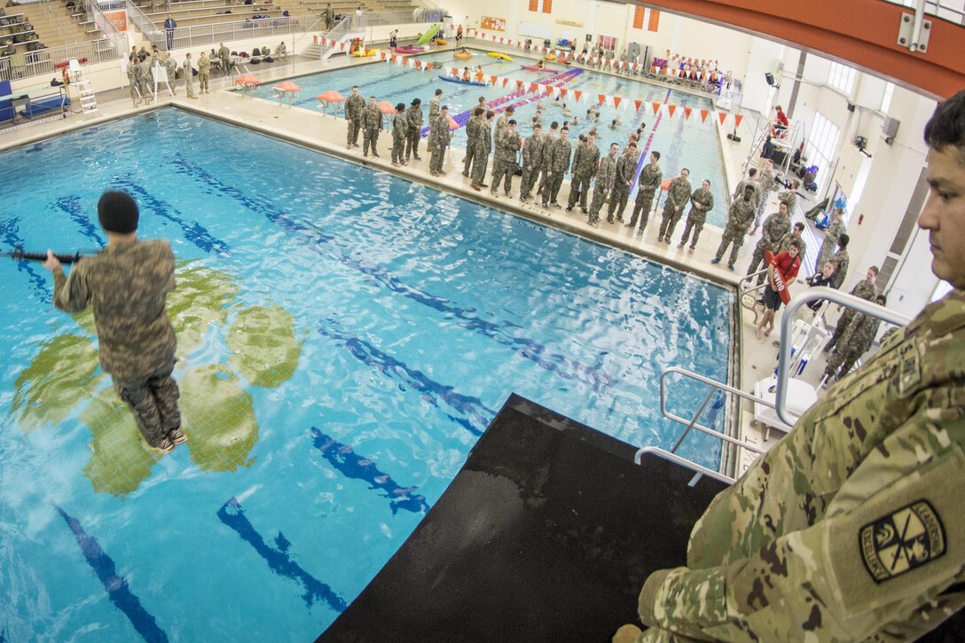 Army Master Sgt. Joe Medrano, right, watches as an ROTC cadet leaps blindfolded into a pool from a 5-meter diving platform carrying an M16 assault rifle during a combat water survival test at Clemson University, S.C., Jan. 28, 2016. Medrano is a senior military instructor. Army photo by Staff Sgt. Ken Scar