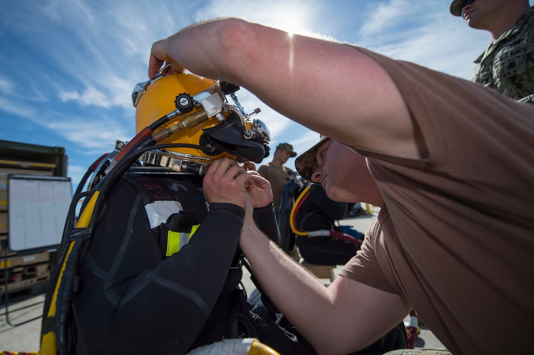 Navy Petty Officer 2nd Class David Miller, right, helps Petty Officer 3rd Class Sean McHugh don a dive helmet for training at Port Hueneme, Calif., Jan. 29, 2016. Miller is a steelworker and McHugh is a builder assigned to Underwater Construction Team 2. Navy photo by Chief Petty Officer Lowell Whitman