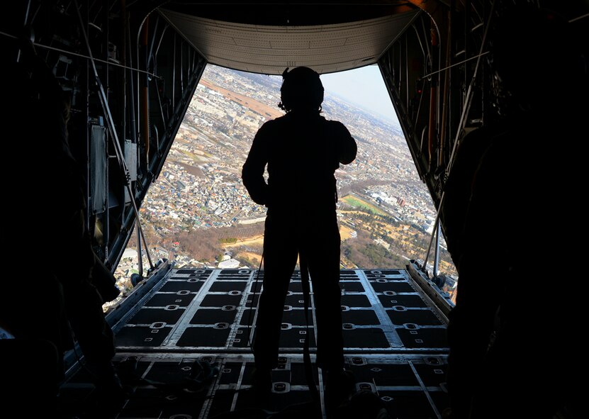 Senior Airman Alexander Lauher, 36th Airlift Squadron C-130 Hercules loadmaster, watches to make sure that each pararescue specialist lands safely on the ground at Yokota Air Base, Japan, Jan. 25, 2016. To ensure safety during personnel drops, loadmasters must be able to multitask between balancing on their feet under turbulence and gravity force while supervising the jumpers and listening over intercom to the aircrew in the cockpit. (U.S. Air Force photo by Airman 1st Class Elizabeth Baker/Released)
