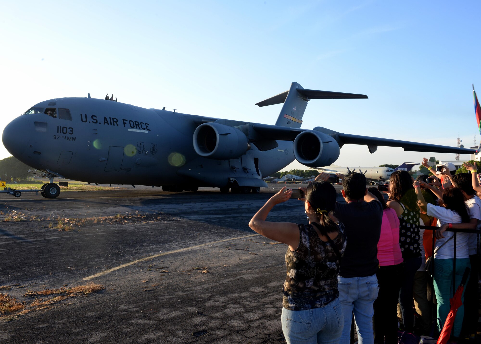 U.S. Air Force members wave to a crowd of people while a U.S. Air Force C-17 Globemaster III cargo aircraft, is being taxied prior to takeoff at Ilopango International Airport in San Salvador, El Savador, Jan. 30, during the 2016 Ilopango Airshow. The C-17 was sent from Altus Air Force Base, Okla., to foster relationships between the U.S. and El Salvador. The aircraft was setup as a static display for the attendees to view and learn about some of its capabilities. (U.S. Air Force photo by Senior Airman Franklin R. Ramos/Released)