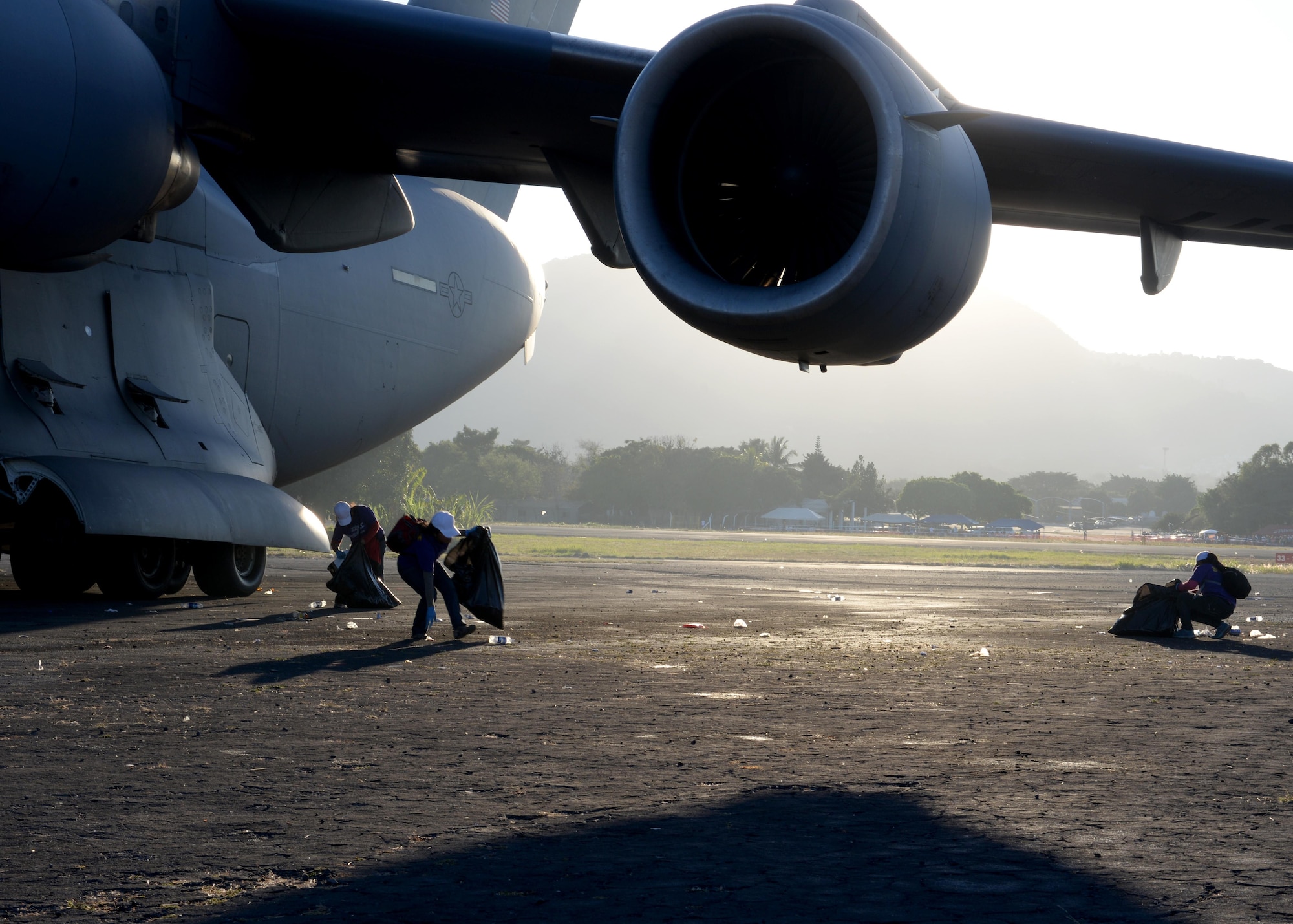 Ilopango Airshow staff, pick up trash around a U.S. Air Force C-17 Globemaster III cargo aircraft, 58th Airlift Squadron, prior to engine startup at Ilopango International Airport in San Salvador, El Savador, Jan. 30, during the 2016 Ilopango Airshow. The C-17 was sent from Altus Air Force Base, Okla., to foster relationships between the U.S. and El Salvador. The aircraft was setup as a static display for the attendees to view and learn about some of its capabilities. (U.S. Air Force photo by Senior Airman Franklin R. Ramos/Released)