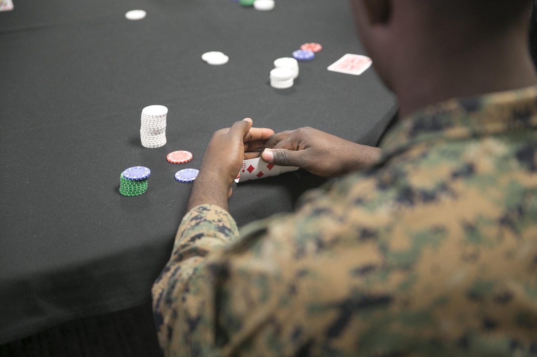 Pvt. Abilassh John, student, Mairne Corps Communications-Electronics School, examines his hand during the Hashmarks Staff Non-Commissioned Officer Club Texas Hold’em Poker Tournament, Jan. 30, 2016. (Official Marine Corps photo by Cpl. Thomas Mudd/Released)