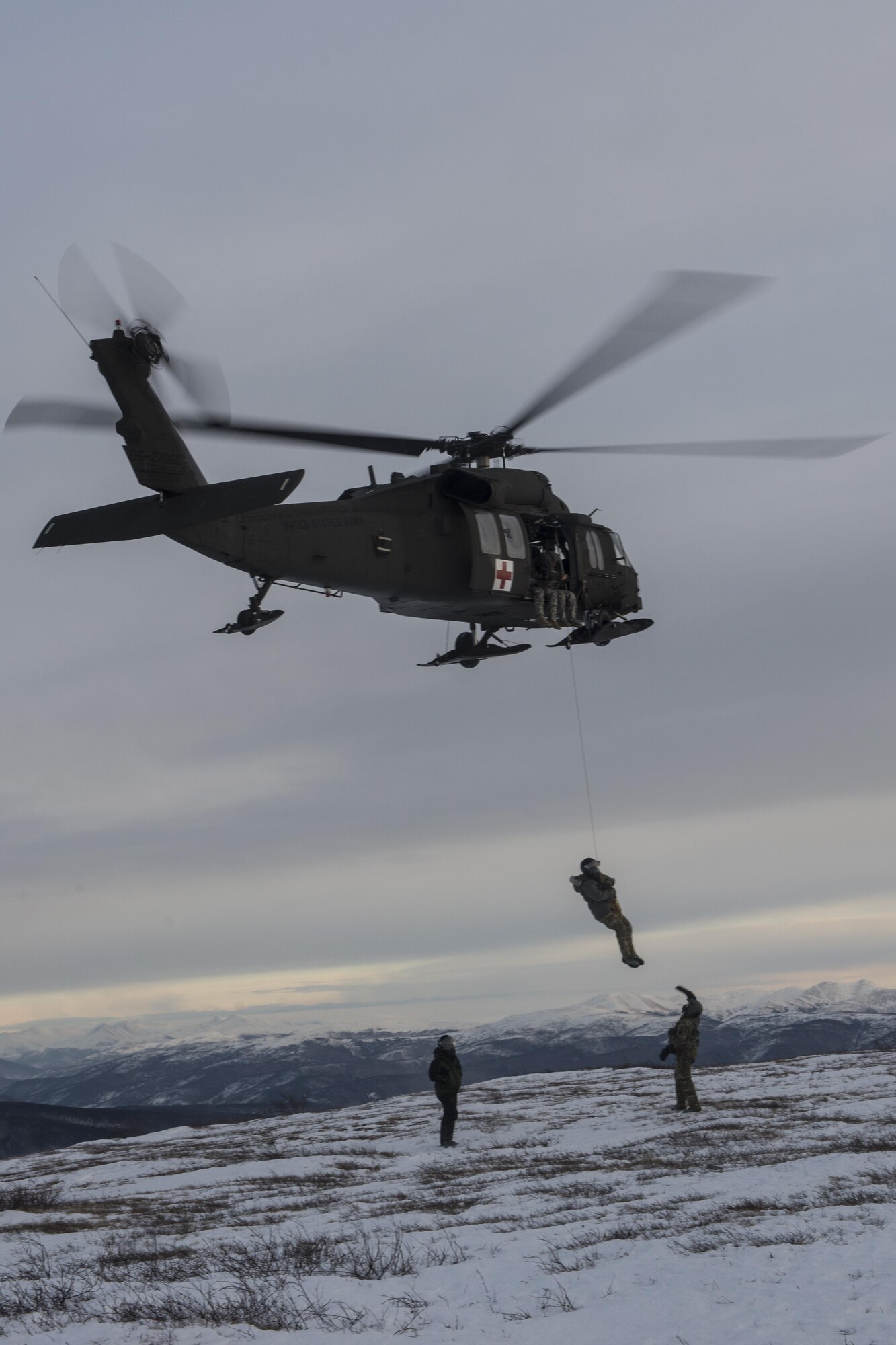 A U.S. Army Uh-60 Black Hawk hoists a student into the air during Survival Evasion Resistance Escape (S.E.R.E) 5-level training Jan 22, 2016, in the Joint Pacific Alaska Range Complex.  Students were hoisted to get experience with rotor wash in extreme arctic temperatures. (U.S. Air Force photo by Staff Sgt. Joshua Turner/Released)