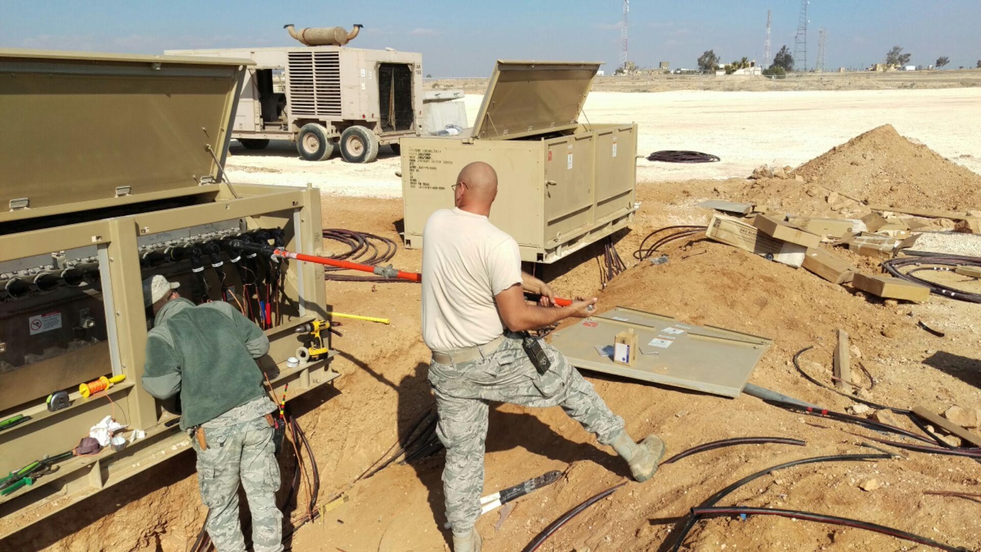 Staff Sgt. Alan Wall (right), an electrical systems craftsman, and Airman 1st Class Patrick Wright, electrical systems journeyman deployed to the 407th Expeditionary, install high voltage cables Dec. 2015. The team was working to bring a second power plant online for future expansions as well as to provide relief to the initial workload power plant. (U.S. Air Force courtesy photo)