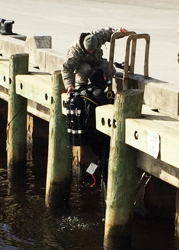 U.S. Army Sgt. David Dilmore assists Spc. Michael Higginbotham, both divers assigned to the 511th Engineer Dive Detachment, as he exits the water after completing repairs to the propeller shaft tube of a damaged U.S. Coast Guard vessel at Marine Corps Air Station Cherry Point, N.C., Jan. 22, 2016. The engineer divers also repaired a crack and holes in the hull of the 110-foot vessel, which allowed the Coast Guard to remove two $3 million engines inside the vessel without significant water damage and maintain the repaired vessel as a training asset while mitigating potential diesel fuel leakage into the surrounding harbor. (Courtesy photo)