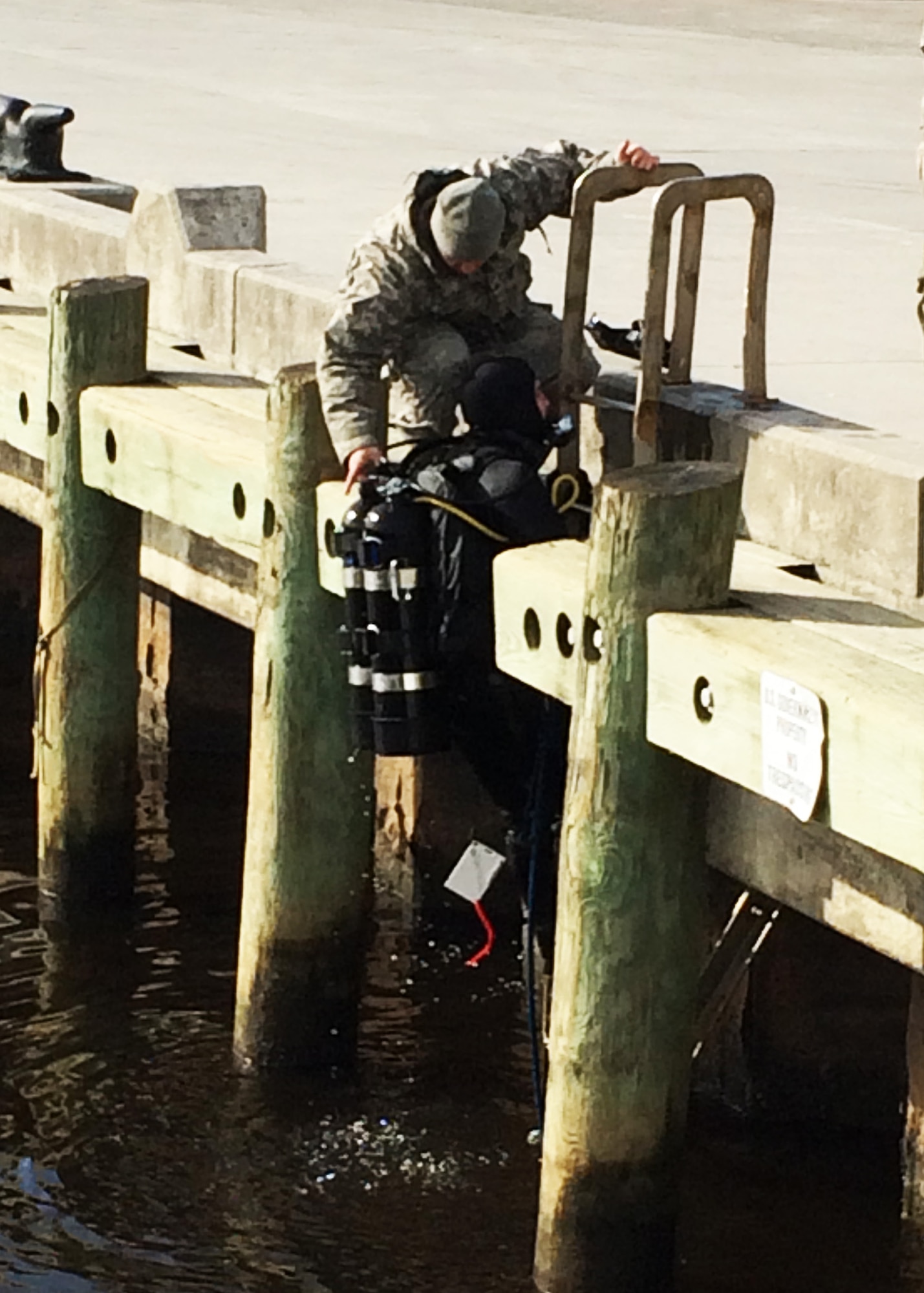 U.S. Army Sgt. David Dilmore assists Spc. Michael Higginbotham, both divers assigned to the 511th Engineer Dive Detachment, as he exits the water after completing repairs to the propeller shaft tube of a damaged U.S. Coast Guard vessel at Marine Corps Air Station Cherry Point, N.C., Jan. 22, 2016. The engineer divers also repaired a crack and holes in the hull of the 110-foot vessel, which allowed the Coast Guard to remove two $3 million engines inside the vessel without significant water damage and maintain the repaired vessel as a training asset while mitigating potential diesel fuel leakage into the surrounding harbor. (Courtesy photo)