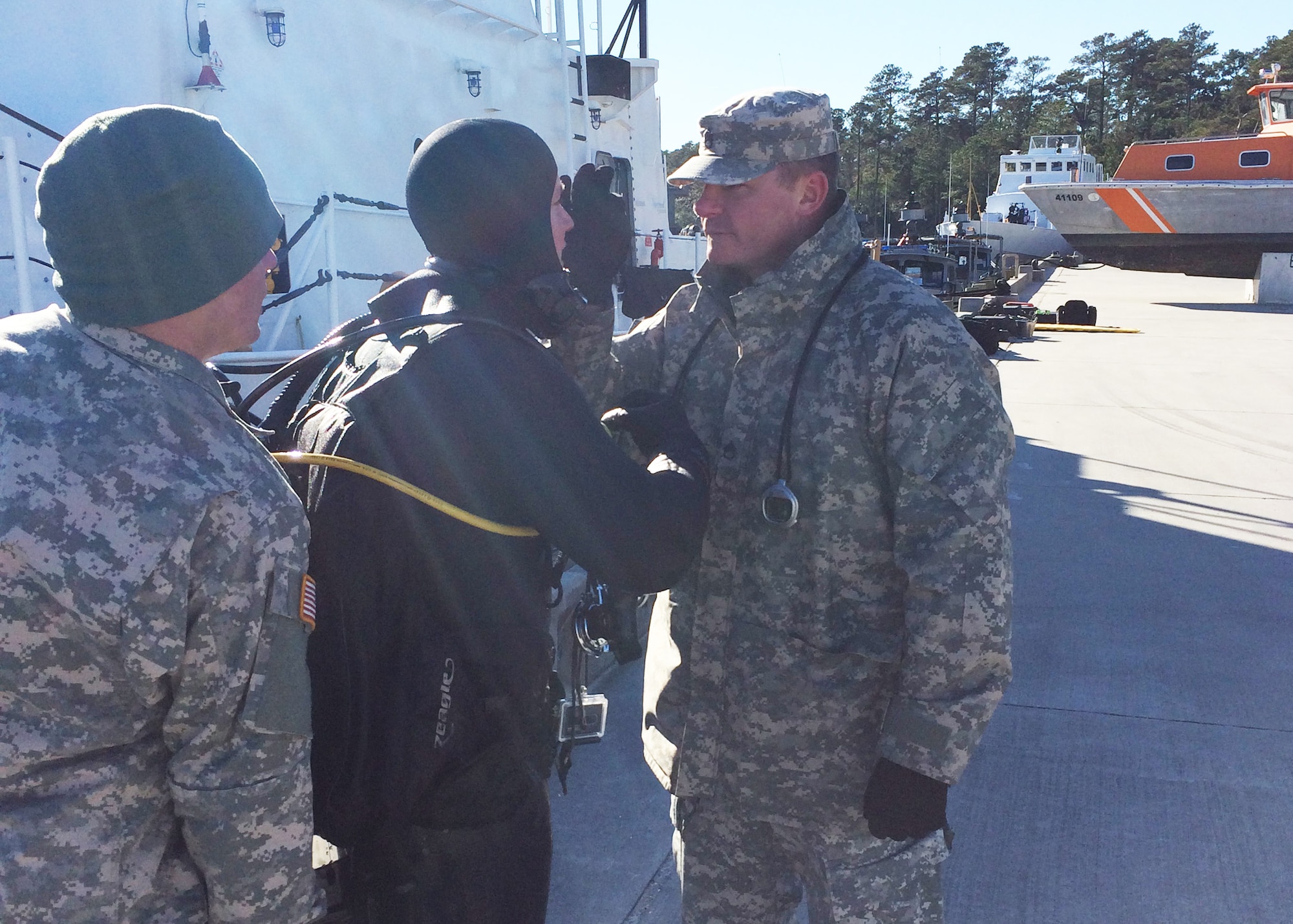 U.S. Army Staff Sgt. Kevin Karraker (right), 511th Engineer Dive Detachment mission noncommissioned officer-in-charge, clears diver Sgt. David Dilmore (center, in scuba gear) after surfacing from a reconnaissance dive at Marine Corps Air Station Cherry Point, N.C., Jan. 19, 2016. The dive supervisor is responsible for examining a diver after surfacing in order to verify the diver experienced no unexpected dive-related casualties during the ascent phase, the most dangerous portion of the dive. (Courtesy photo)
