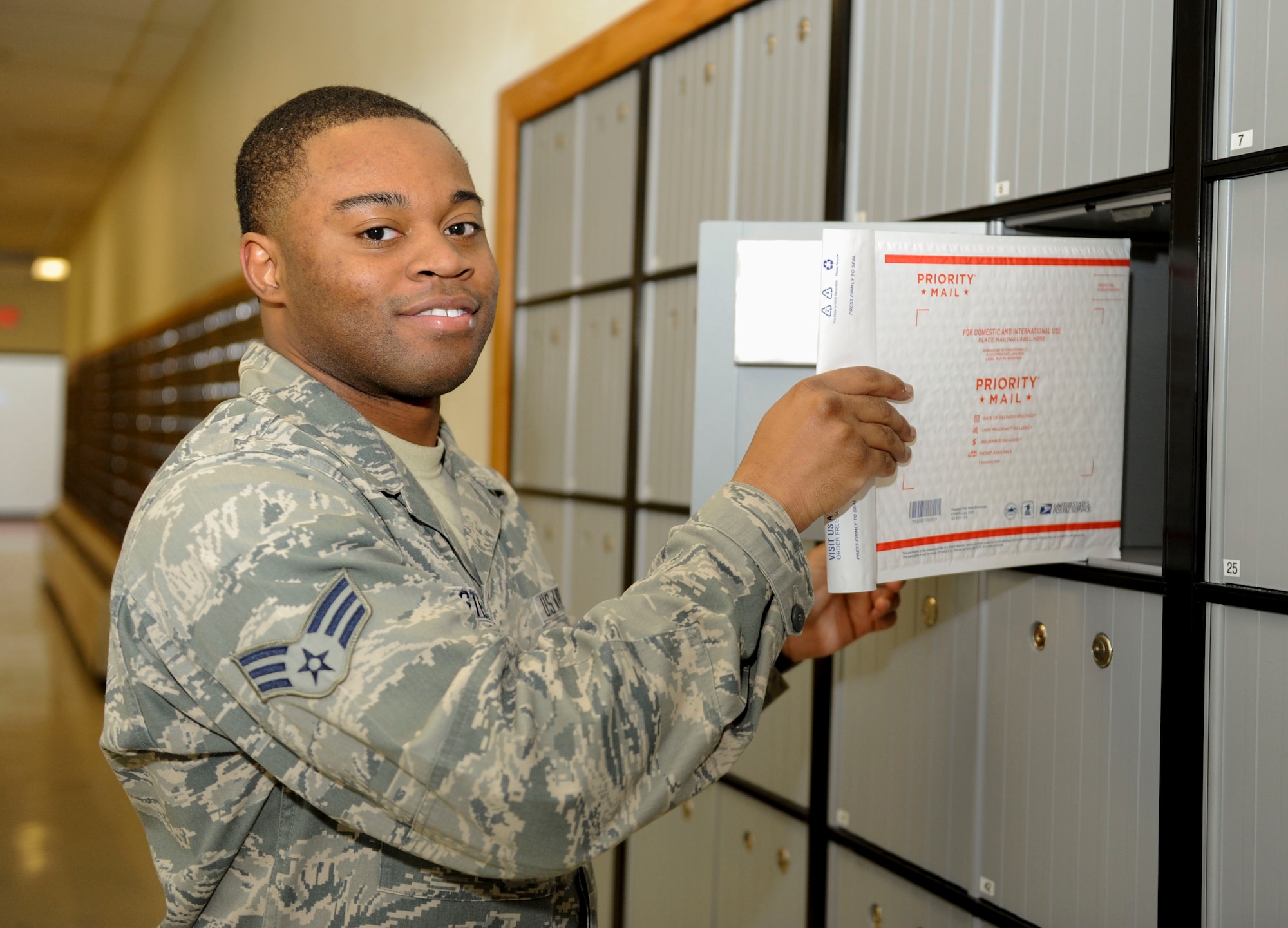 Senior Airman Rashaad Stewart, 5th Communications Squadron knowledge manager, poses with a package next to the new P.O. boxes at Minot Air Force Base, N.D., Jan. 14, 2016. With the new P.O. box system in-place, Airmen who cannot pick up their mail during normal Postal Service Center operating hours now have an opportunity to receive their mail 24/7. Dorm residents will receive a key in their mailbox allowing them to go the post office at any time and retrieve their package. (U.S. Air Force photo/Senior Airman Sahara L. Fales)