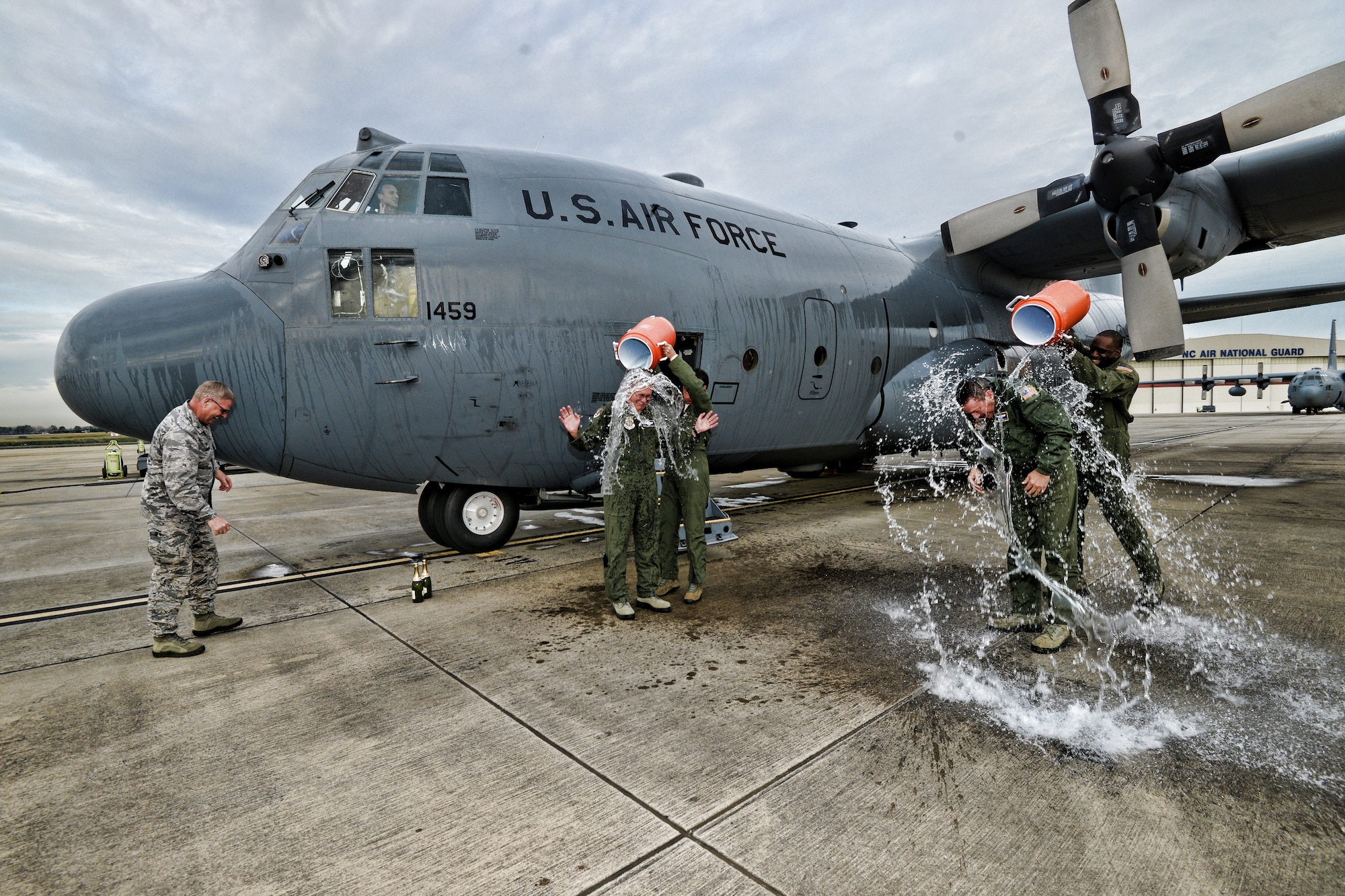 In a longstanding military tradition, U.S. Air Force Master Sgt. Pennie Brawley (left) douses Vice Wing commander, Col. Quincy “Newt” Huneycutt, III, with ice cold water as Senior Master Sgt. Jermaine Parker (right), does the same to Chief Master Sgt. Andrew “Andy” Huneycutt after the brothers exit the 145th Airlift Wing, C-130 Hercules aircraft for the last time at the North Carolina Air National Guard Base, Charlotte Douglas International Airport. Combined, the brothers leave the 145th Airlift Wing with over 72 years of honorable military service. (U.S. Air National Guard photo by Staff Sgt. Yolanda Addison /Released)