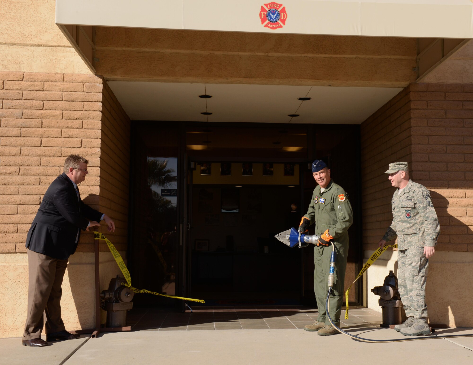 FROM LEFT: Ron Sites, Fighter Country Partnership president and executive director, assists Brig. Gen. Scott Pleus, 56th Fighter Wing commander, during the ribbon-cutting ceremony Jan. 20 unveiling the newly renovated fire station at Luke Air Force Base. The renovations include remodeled rooms, high-efficiency lighting and new interior paint. Chief Master Sgt. Christopher Horsman, 56th Civil Engineer Squadron Luke Fire Department fire chief, was also on hand.