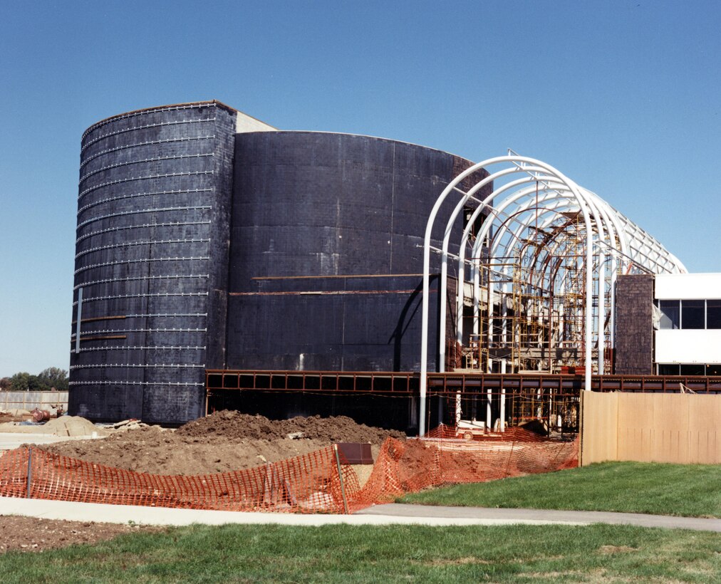 In October 1989 the Air Force Museum Foundation awarded a contract to the B.G. Danis Company/Building Division of Dayton for the construction of an IMAX Theatre. The 500-seat IMAX Theatre, constructed in front of and connected to the existing museum buildings, opened in May 1991. An 80-foot-high glass atrium over the expanded lobby serves as the architectural focal point for the entire $7.3 million complex. The theatre underwent an $800,000 renovation in 2012 as part of its conversion to a 400-seat digital 3D theatre. 1990 Construction photo. (U.S. Air Force Photo)